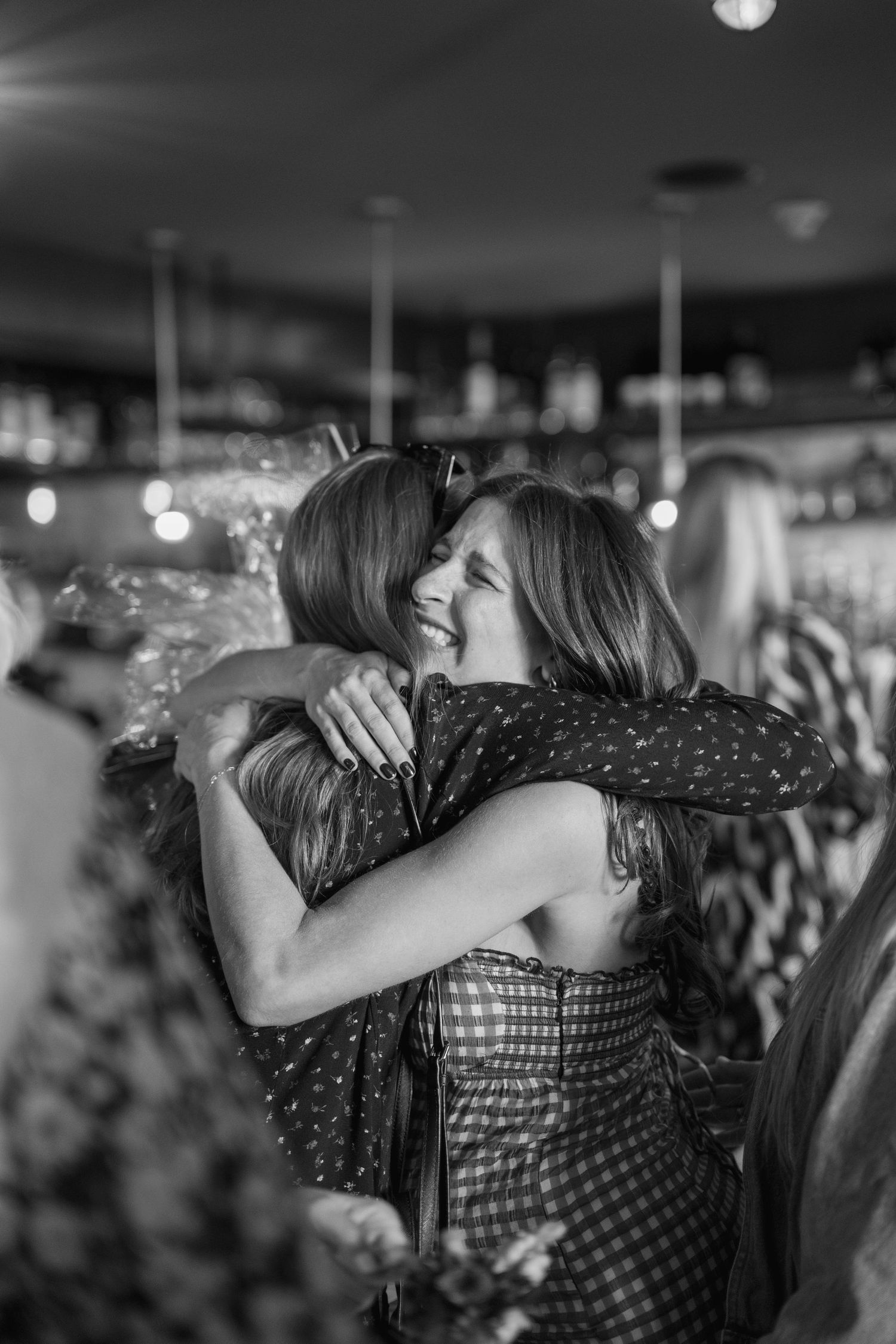 A sequence of black and white photos showing people embracing in a crowded venue.