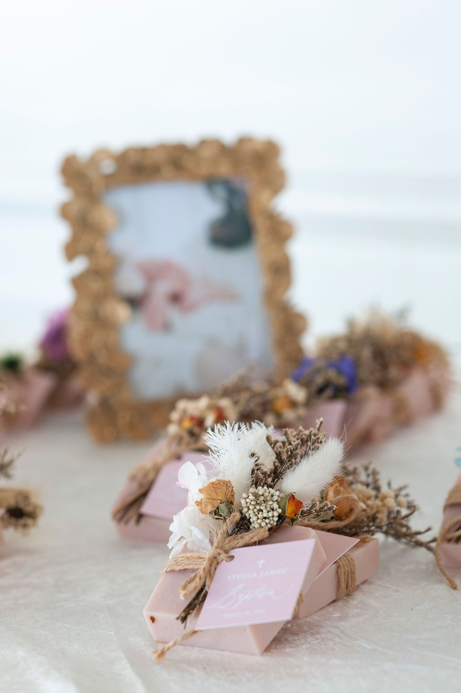 Decorative pink and gold frames with dried flowers arranged on a light surface.