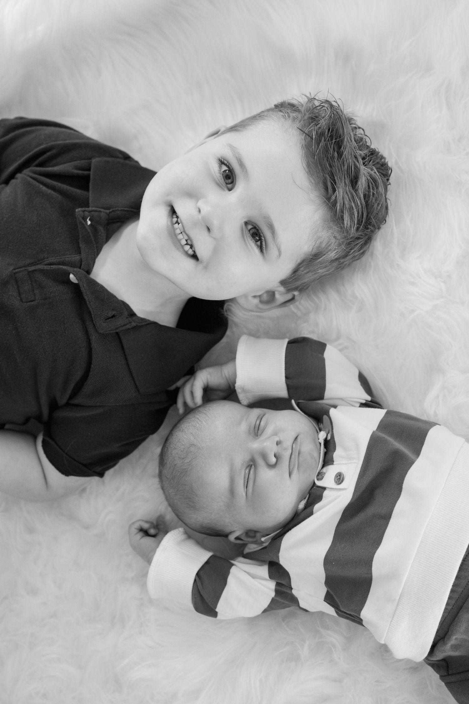 Black and white portraits of two children lying together and sharing sweet moments.