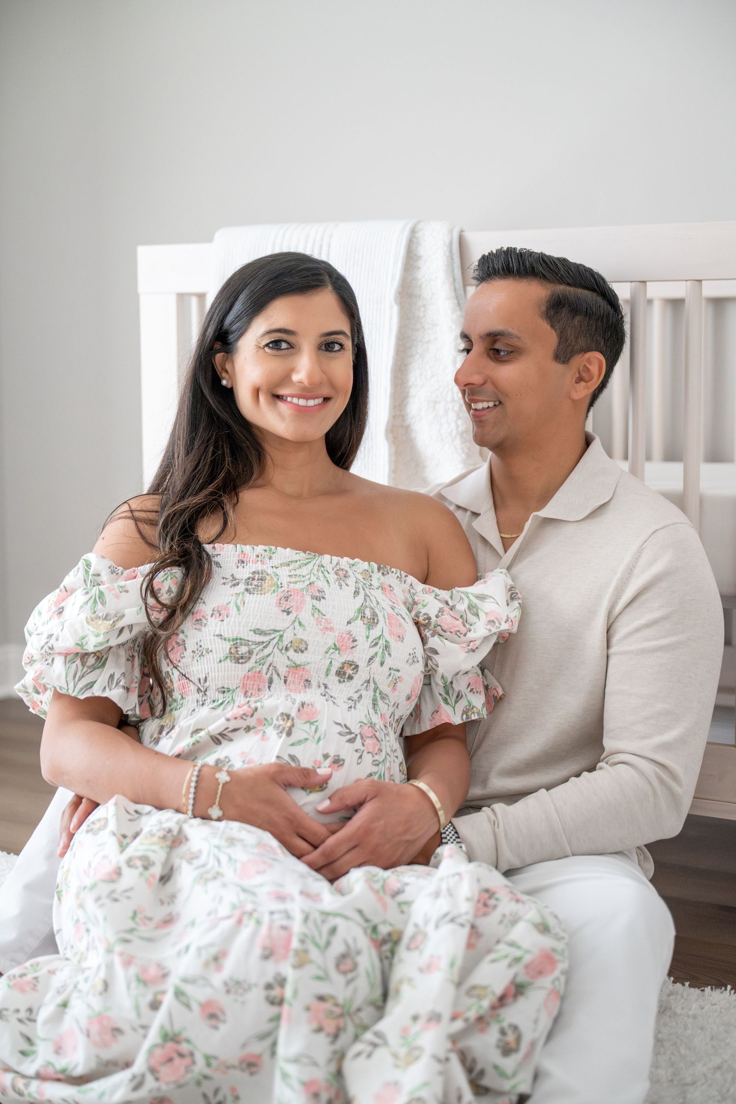 A couple in coordinating white outfits shares intimate moments on a white couch indoors.
