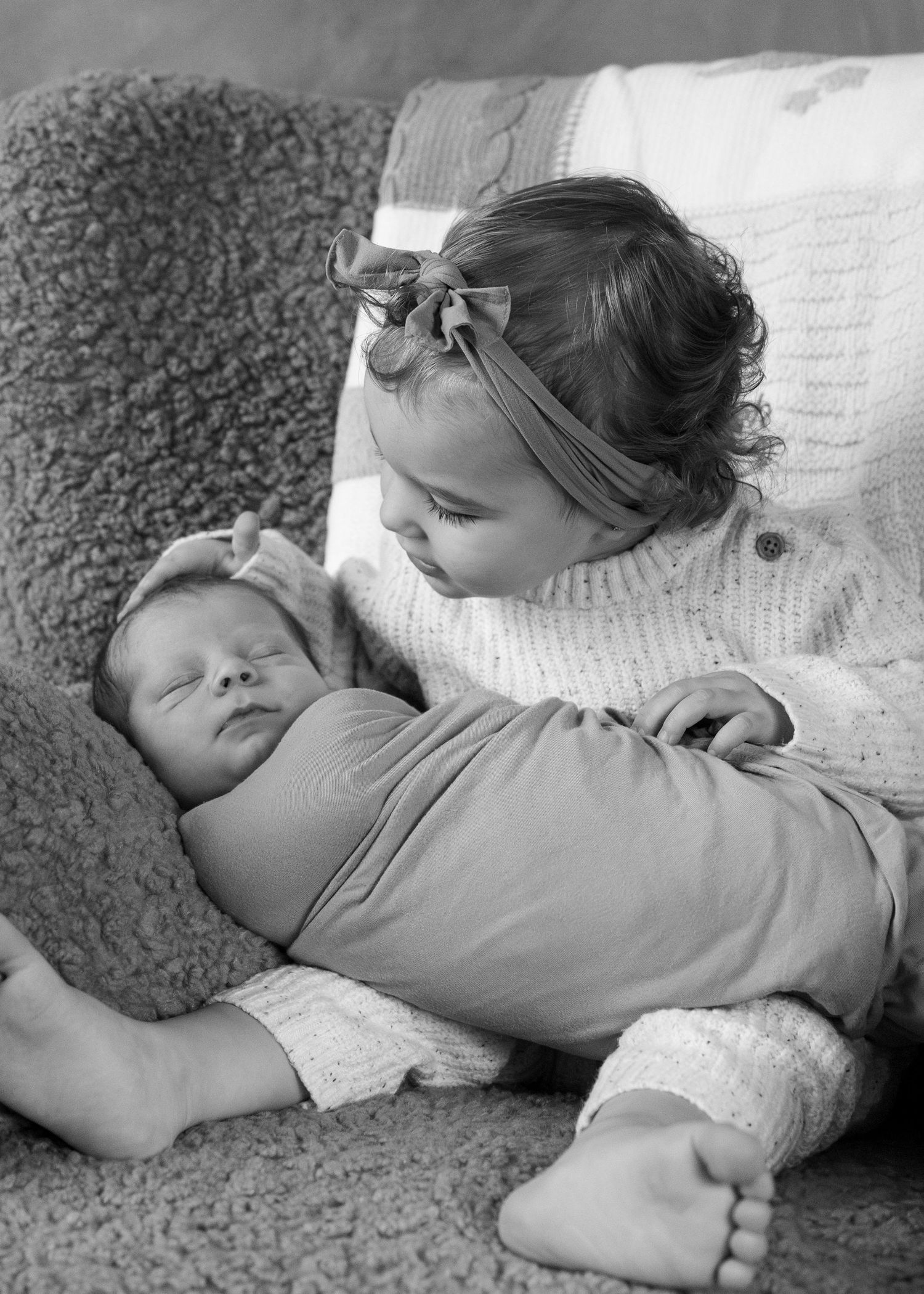 A black and white photo shows a small figure resting peacefully on a textured couch.