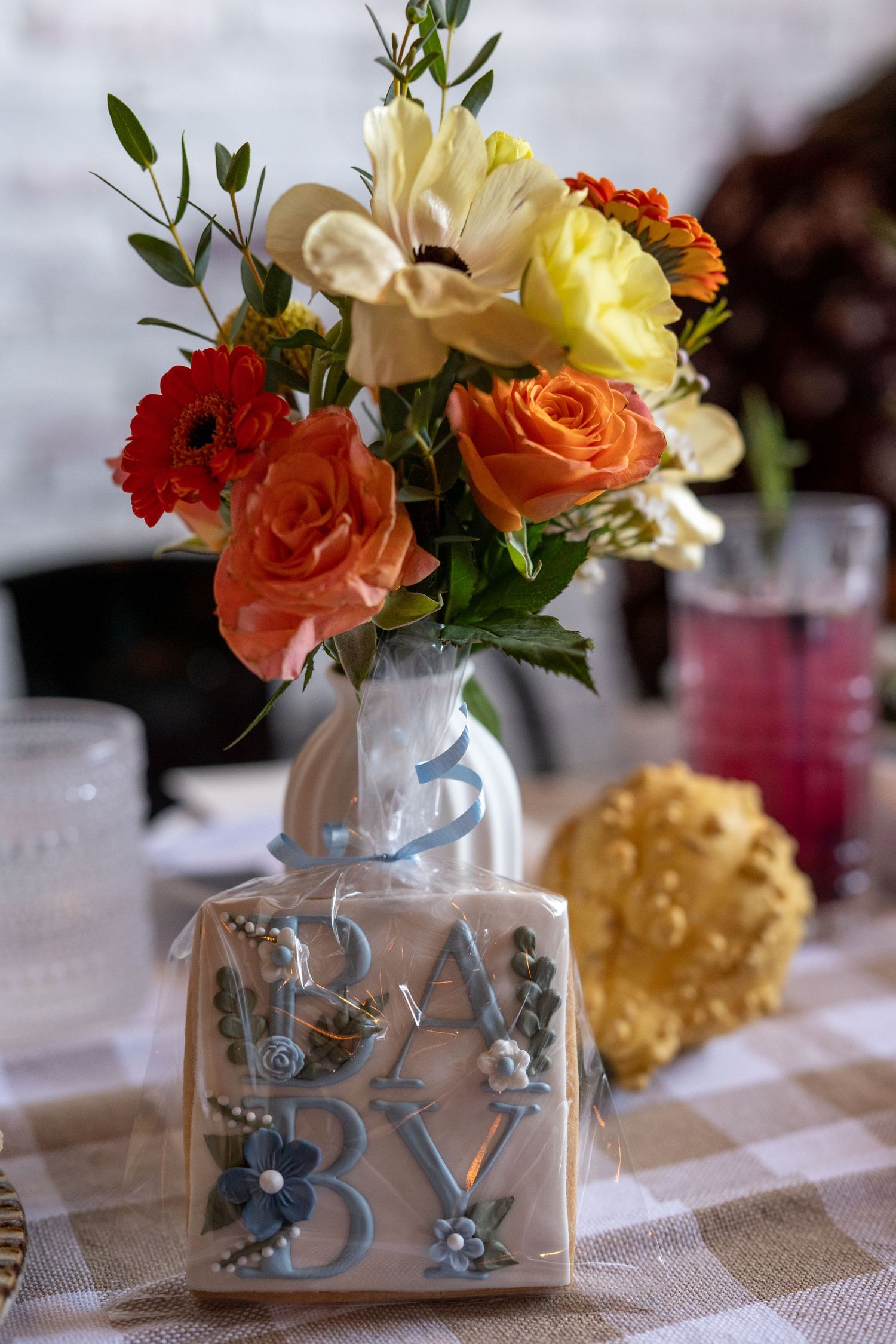 Decorative flower arrangements in 'BABY' lettered vases as table centerpieces.