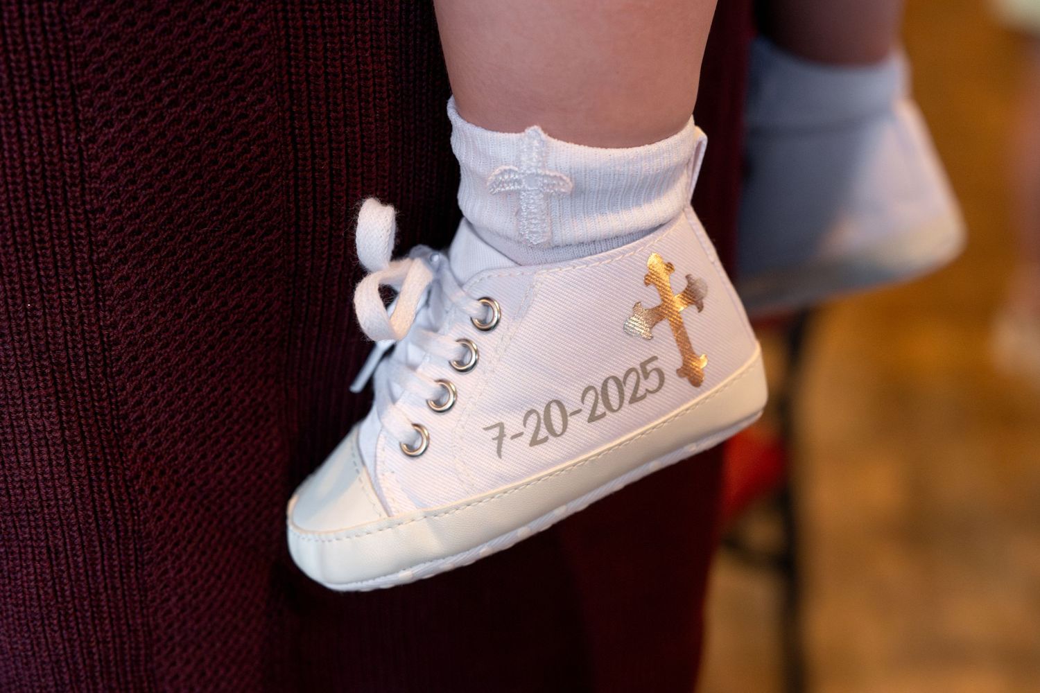 A series of white baby shoes arranged in a row showing different angles of the same style bootie.