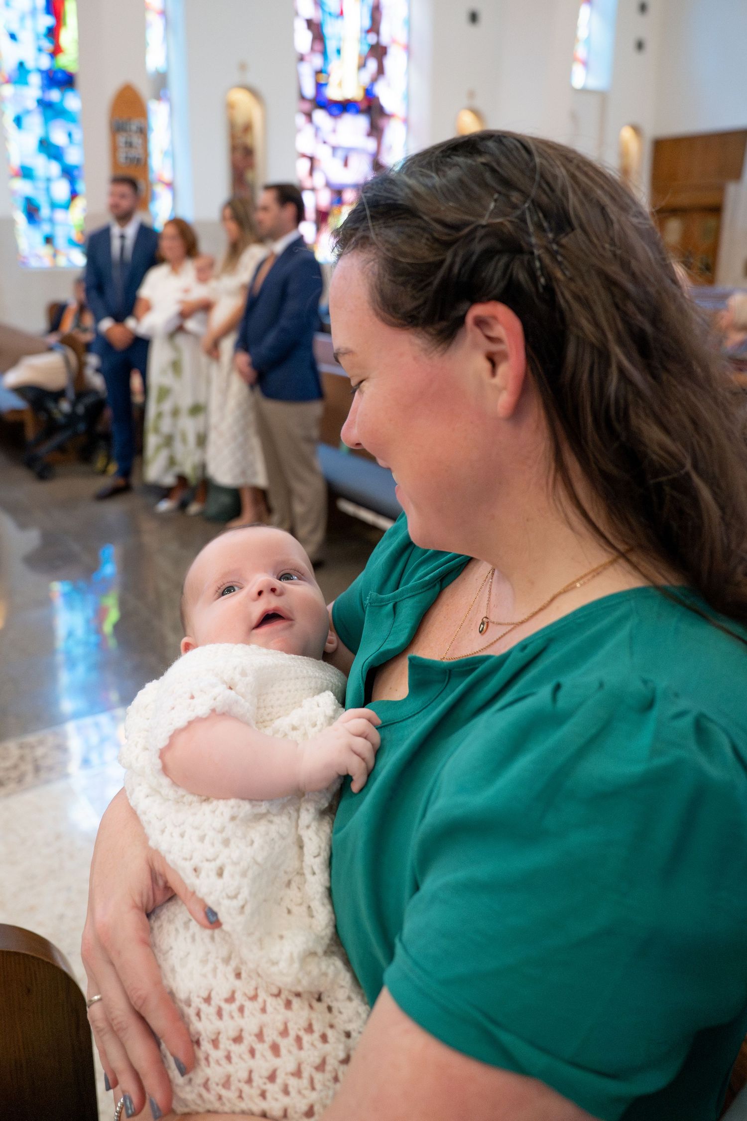 A series showing tender moments between a baby in white dress and someone in green during a church ceremony.