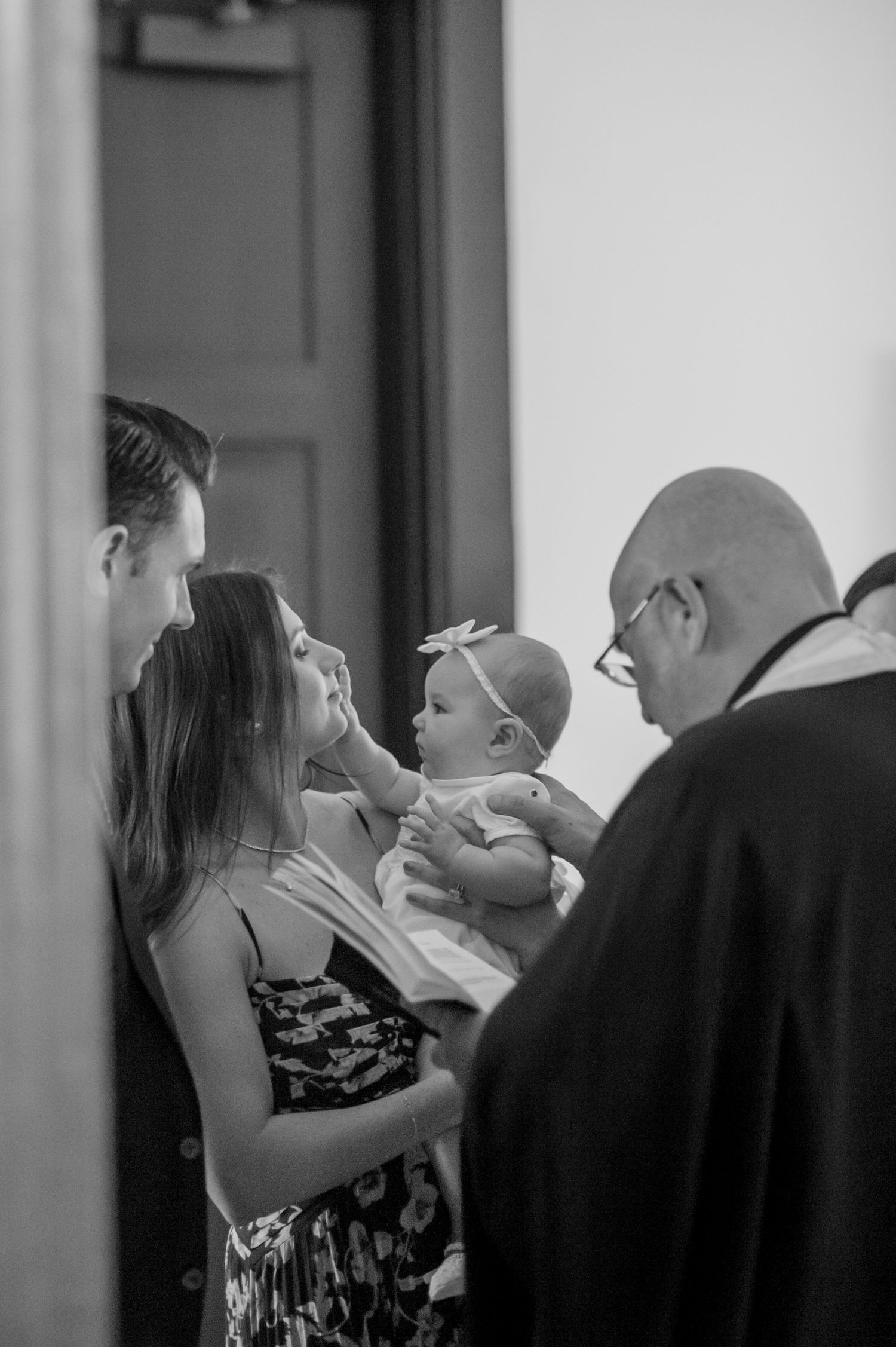 Black and white photos capturing an intimate baptism ceremony with family members gathered around a baby.