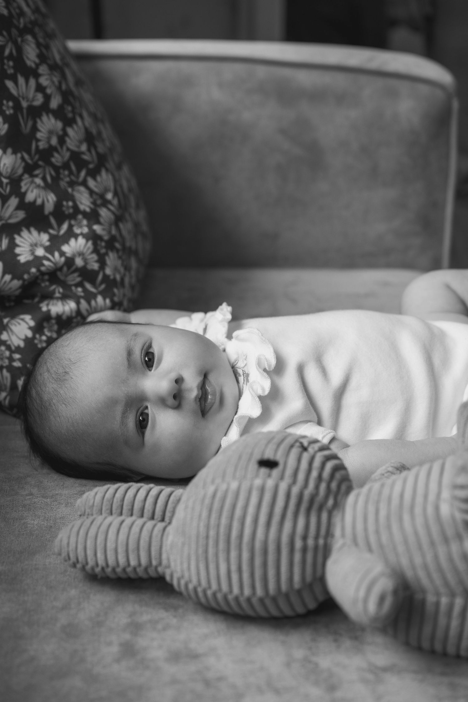Black and white portraits of baby lying on textured surface wearing striped outfit.