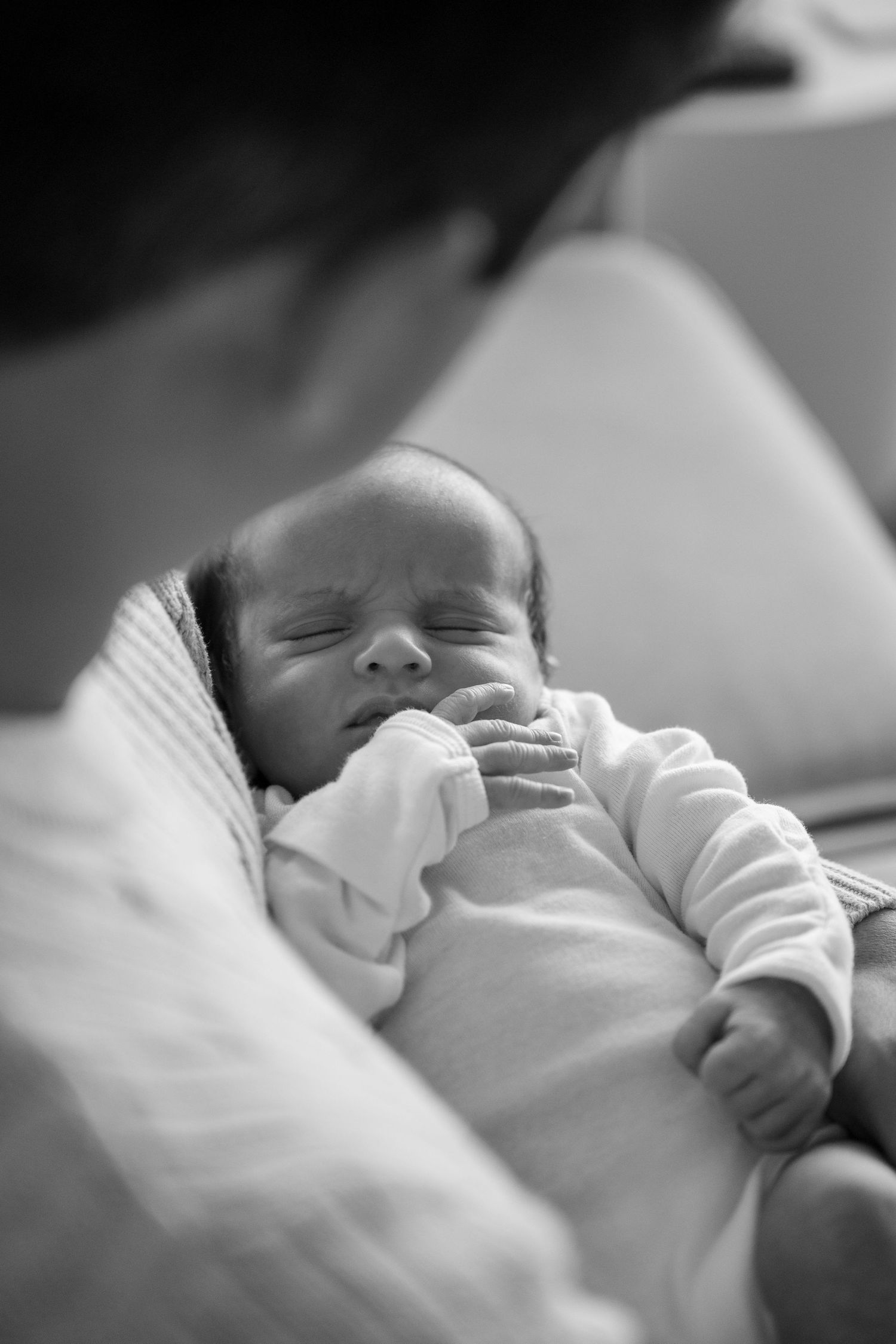 Peaceful sleeping newborn baby in white clothing against soft background.