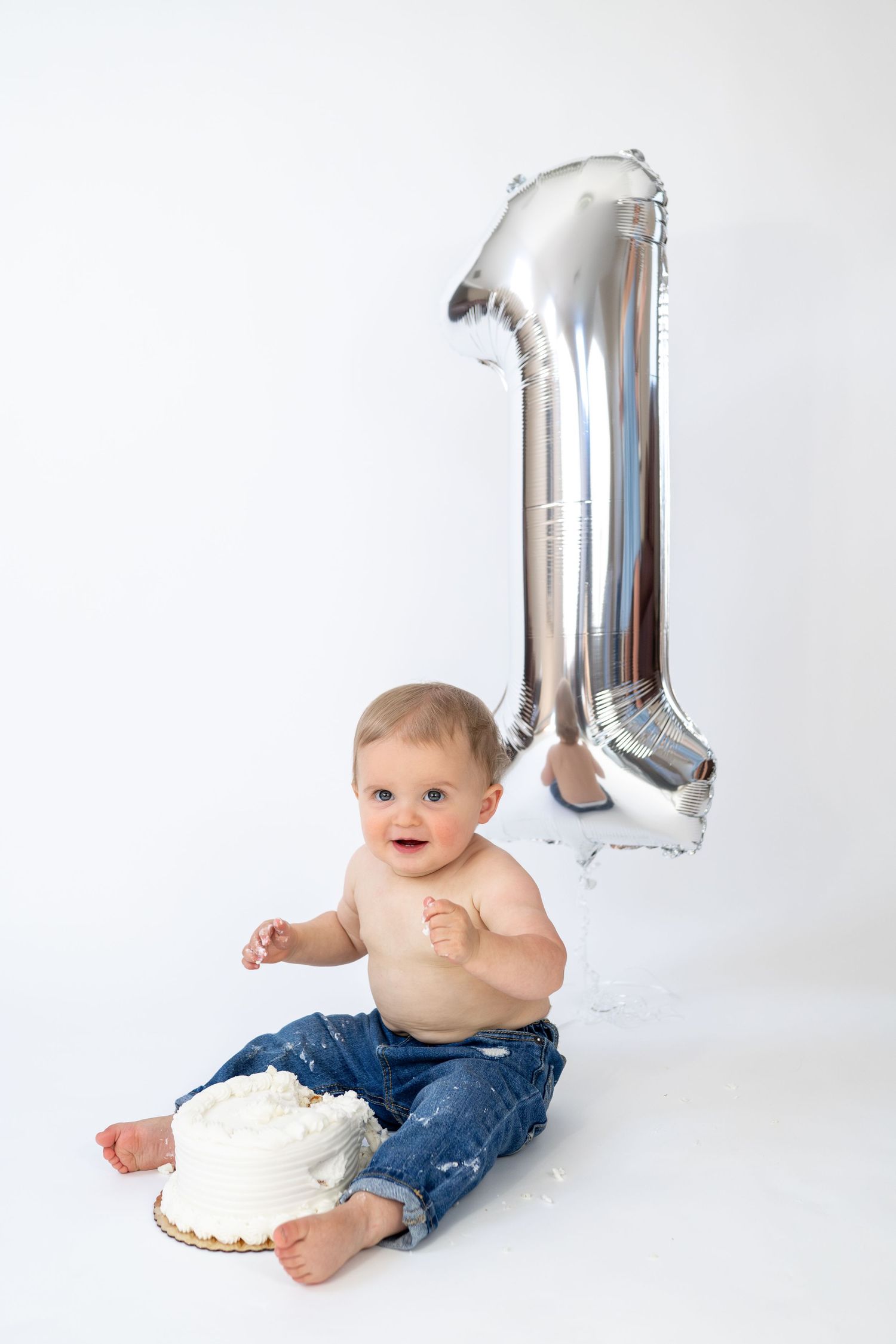 Baby's first birthday cake smash with silver number one balloon on white background.
