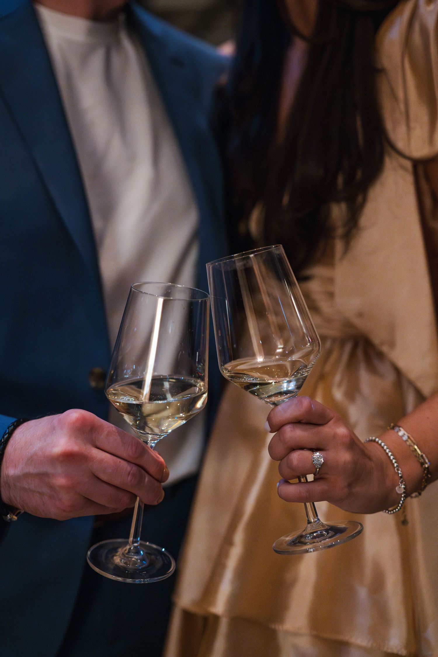 Two wine glasses clink together in a celebratory toast against a dark background.