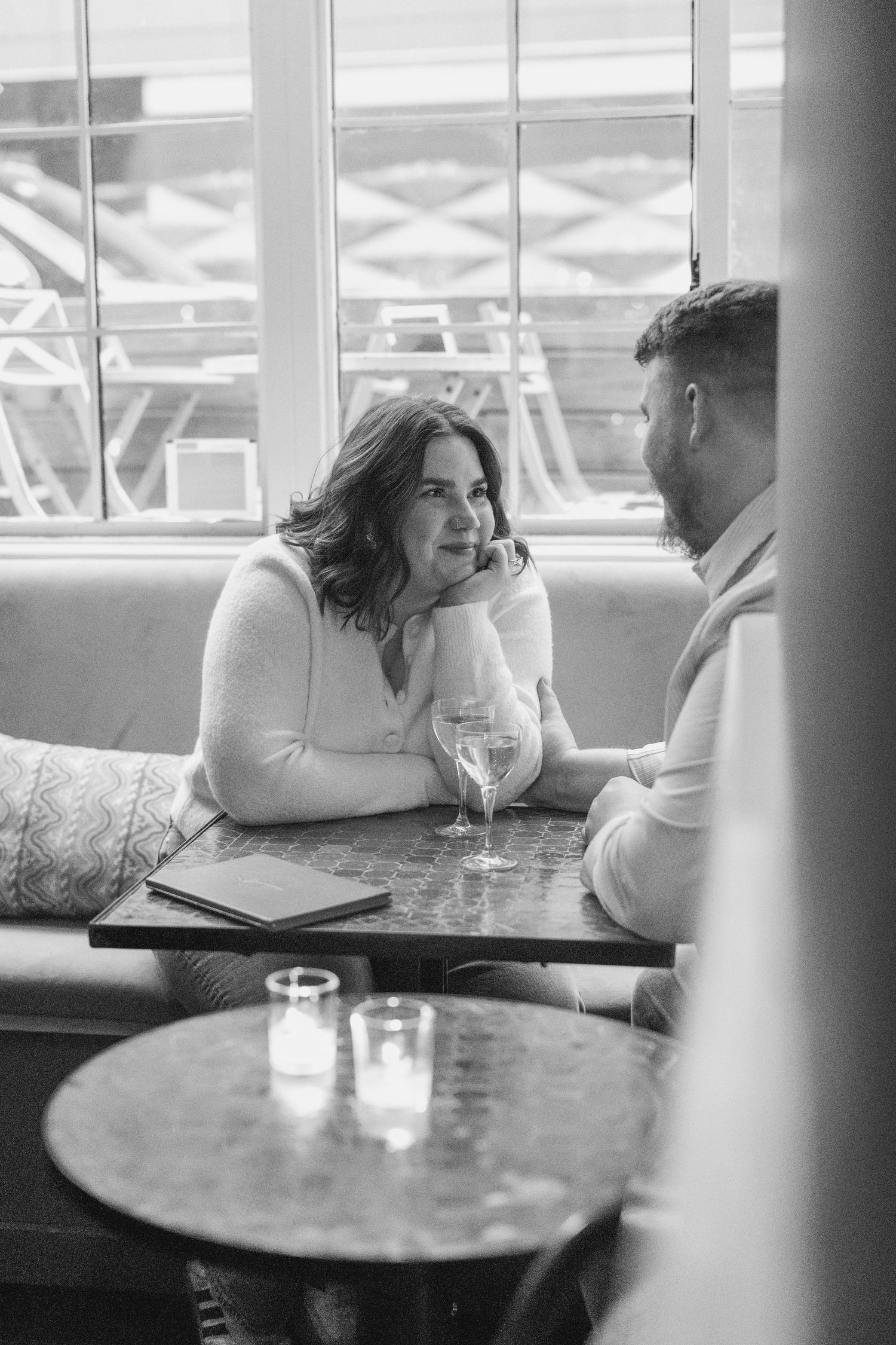 A couple sharing an intimate conversation at a dimly lit restaurant table.