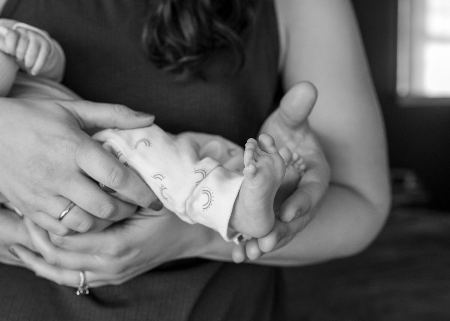 Black and white photo sequence showing hands gently holding and examining a small newborn baby.