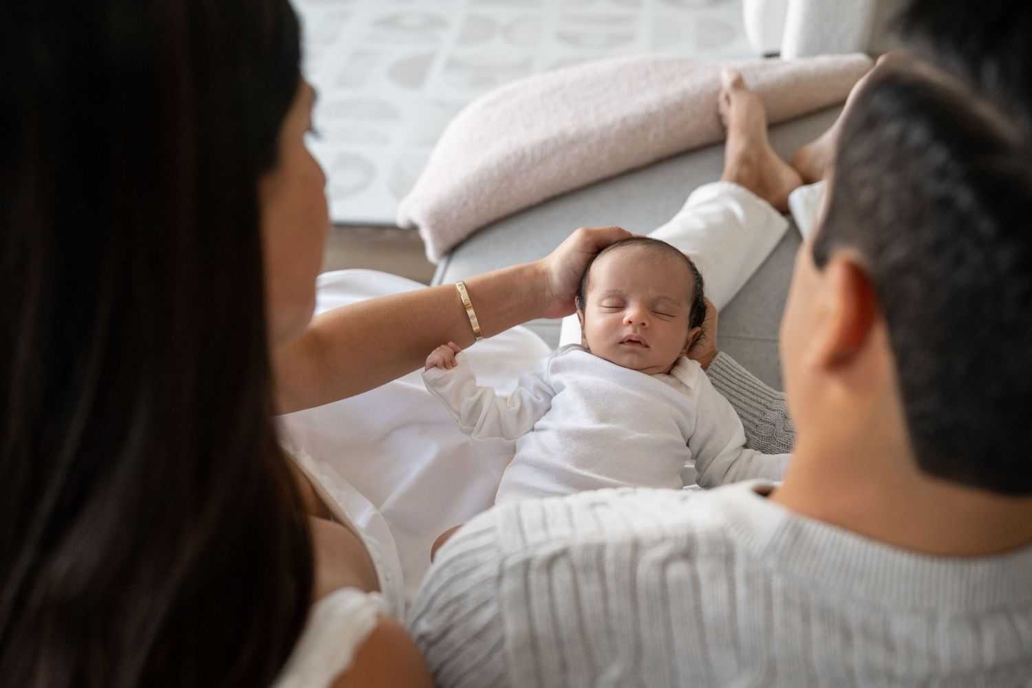 Newborn baby sleeping peacefully while being admired by parents.