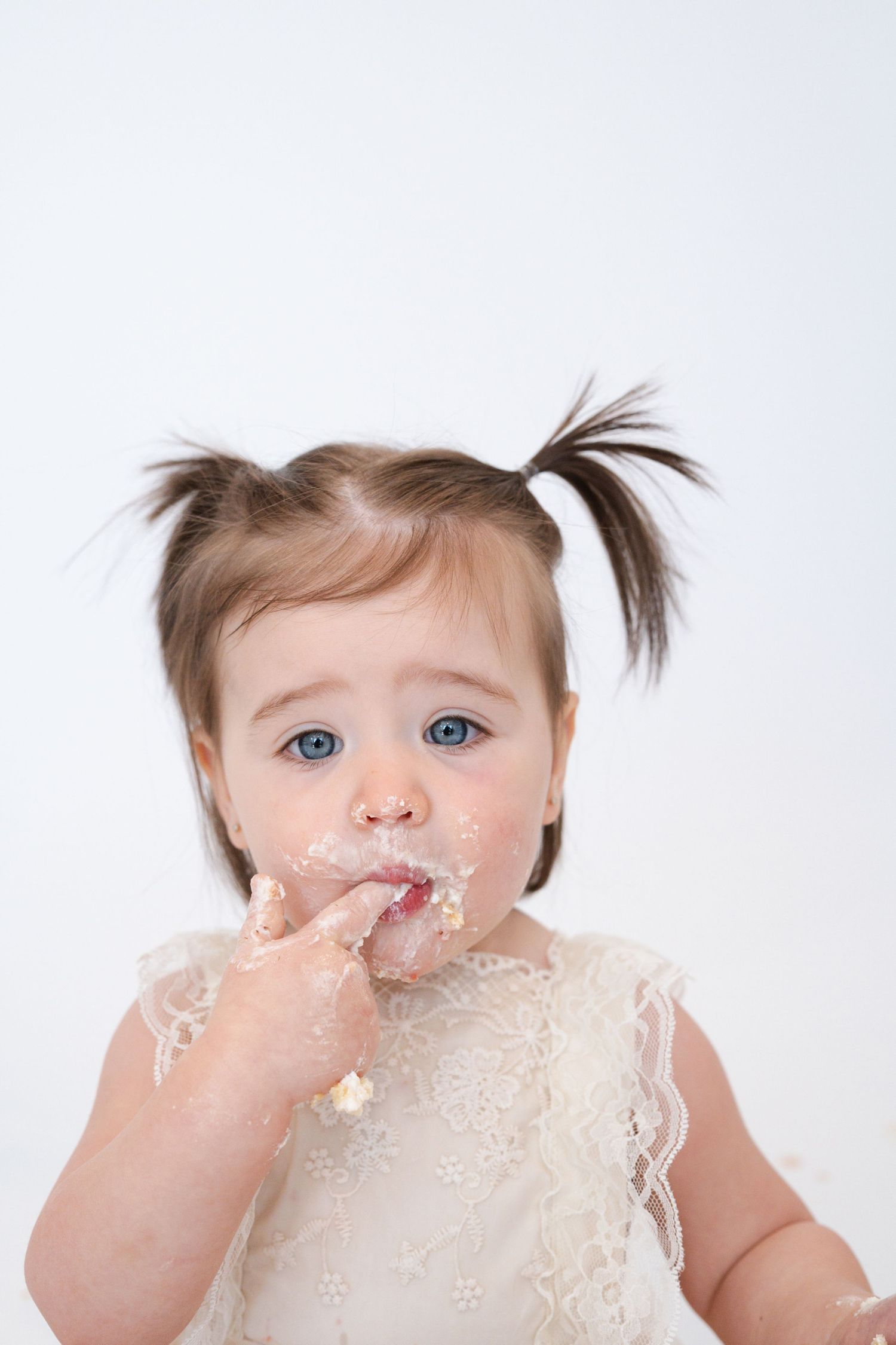 Close-up shots of baby getting frosting on face during cake smash photo session.