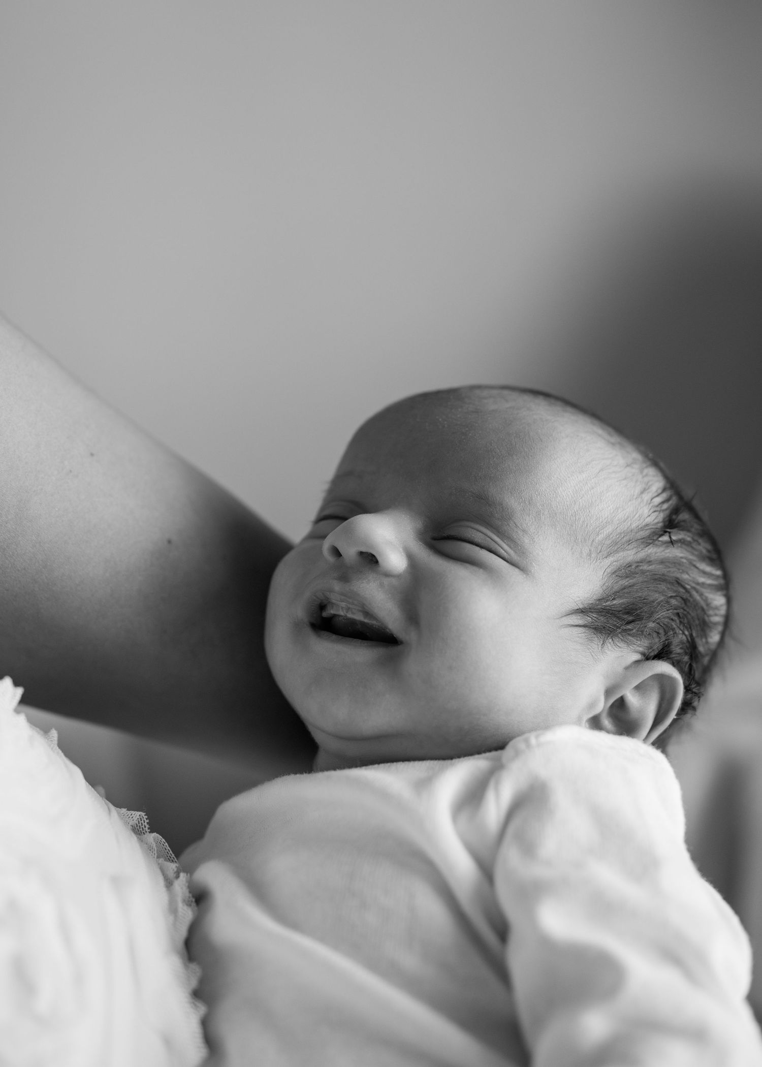 Side profile of sleeping newborn in soft natural lighting.