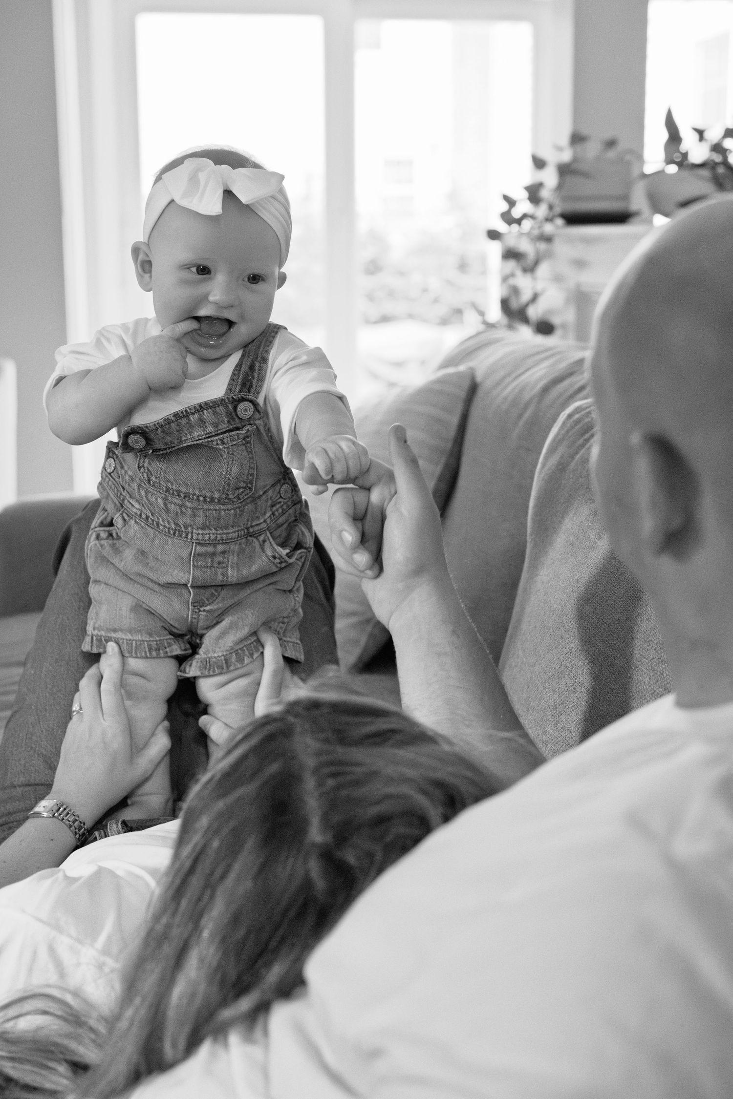 Black and white photo series showing playful moments between family members on a couch.