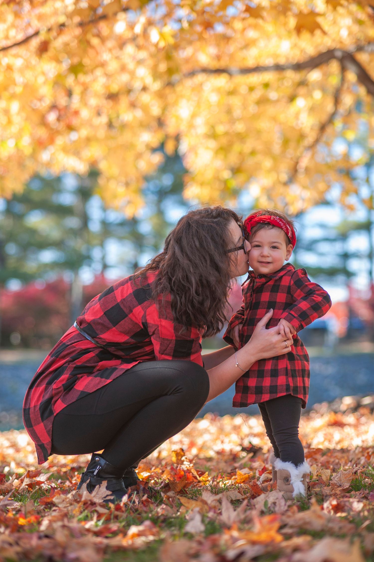 A series of candid moments in autumn leaves showing playful interaction between parent and child in matching buffalo plaid.