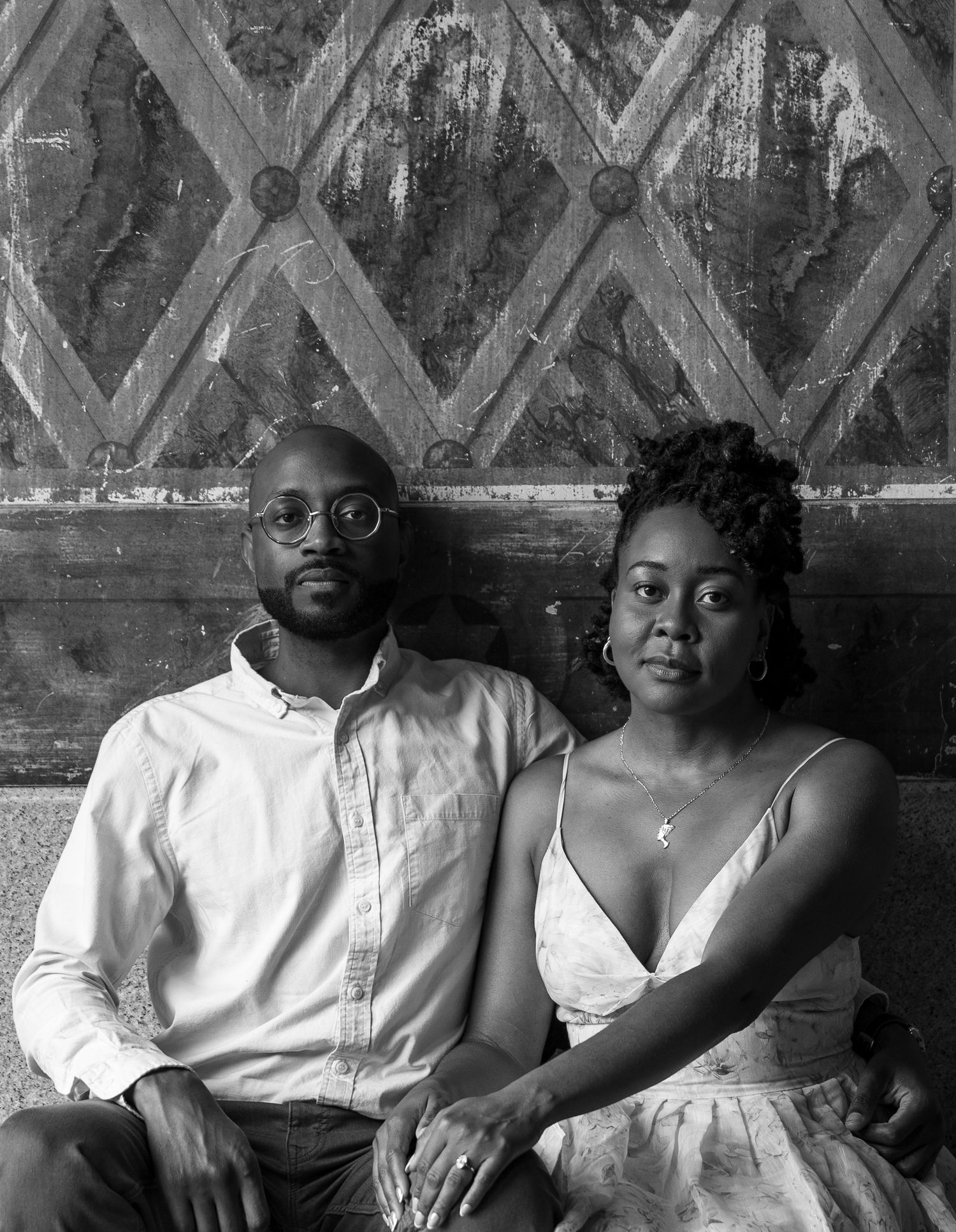 Black and white portrait series showing a couple sitting together in formal attire against a patterned backdrop.