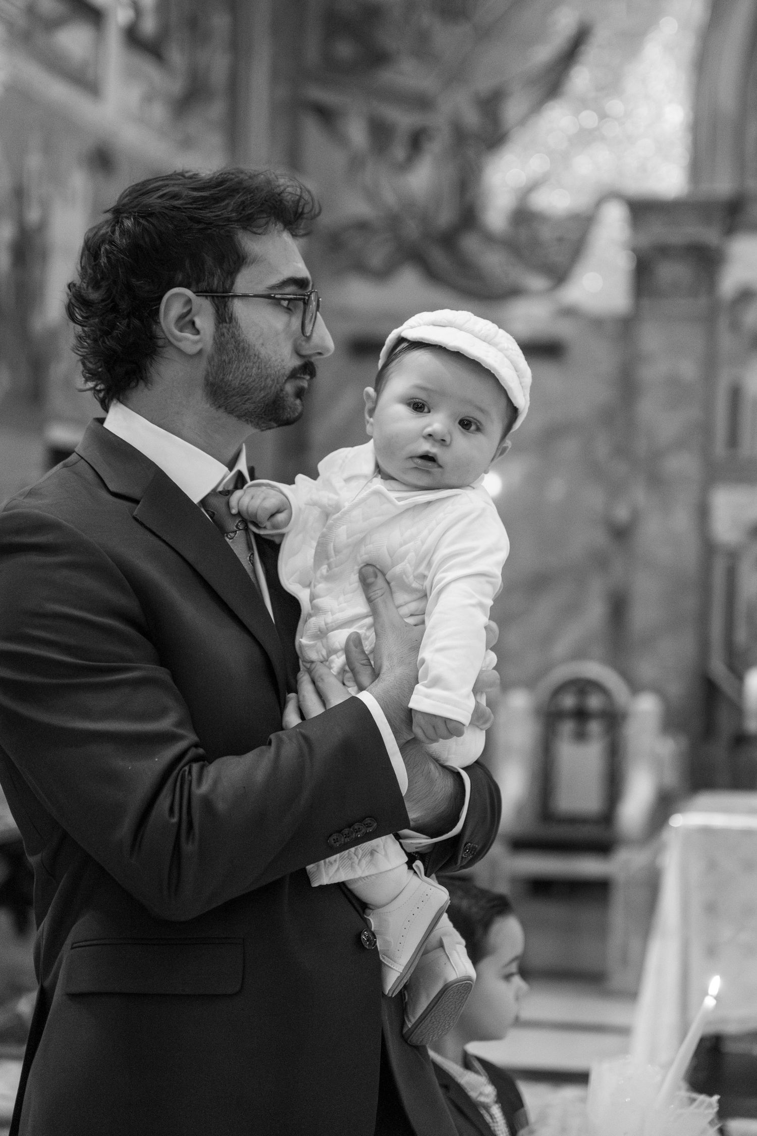 A series of black and white photos showing tender moments between a parent and baby in formal attire.