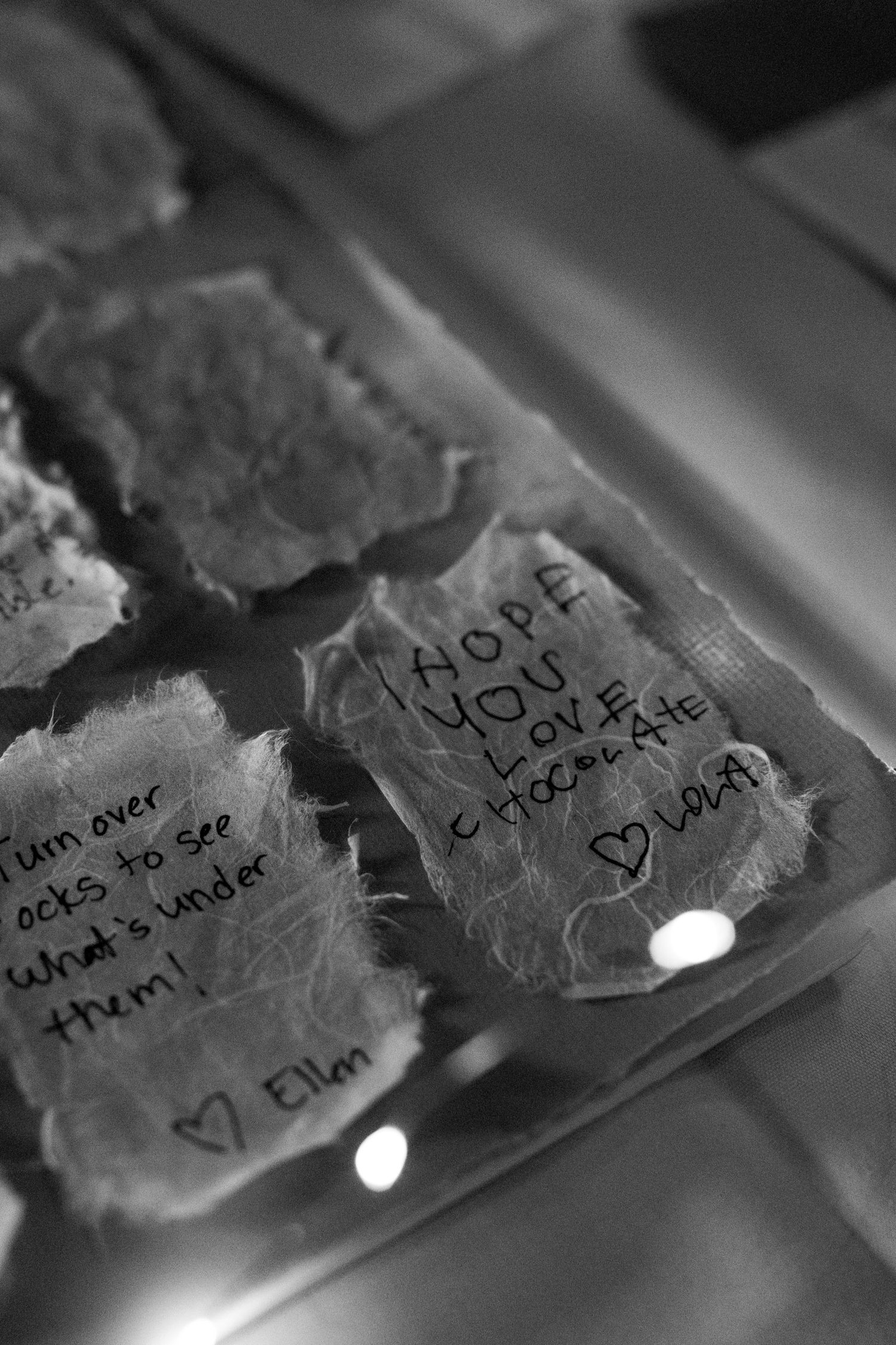 Handwritten love notes on torn pieces of paper arranged in a row with soft lighting.