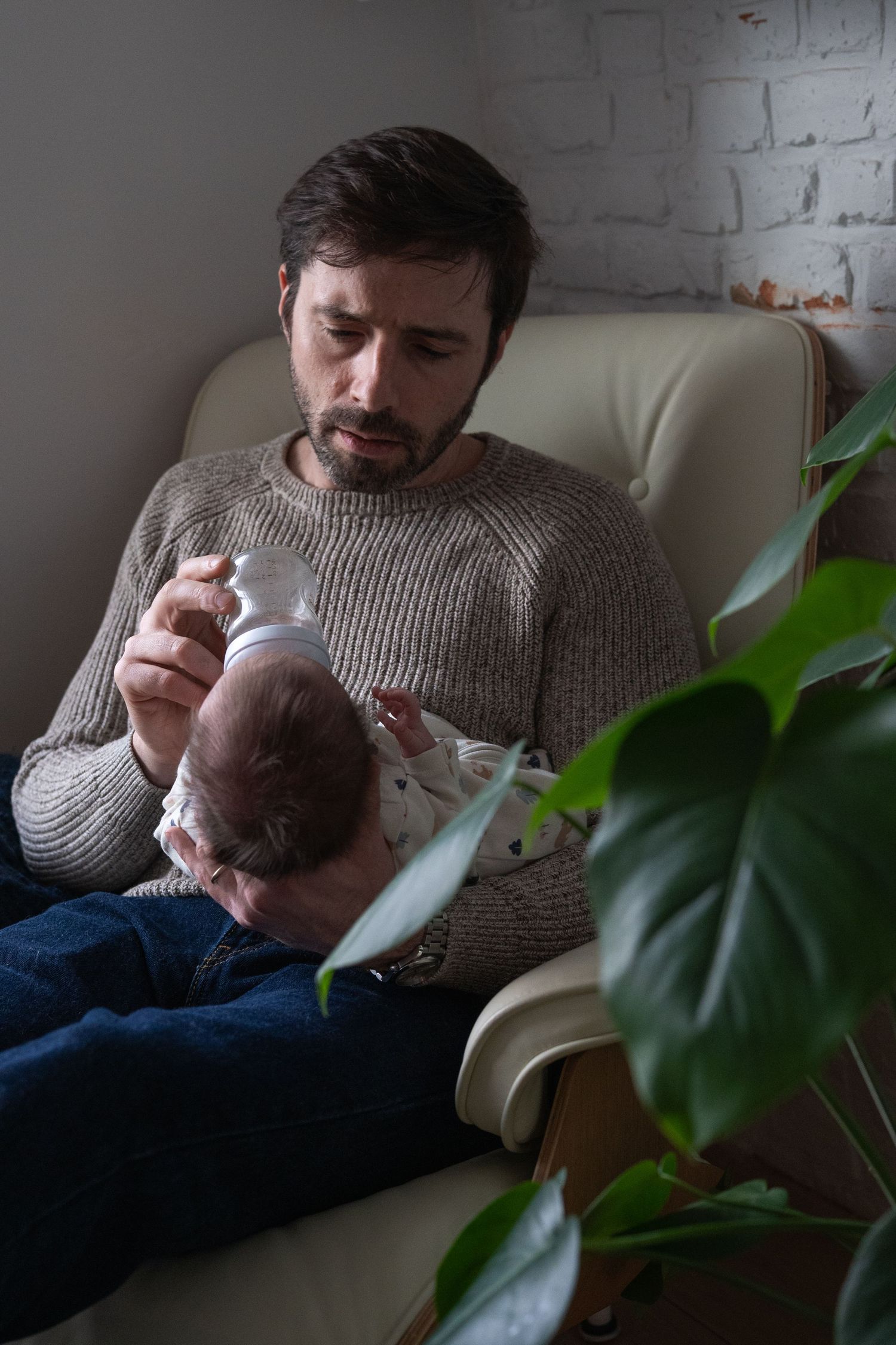 Quiet moments shared on a cream-colored couch with houseplants and bookshelves.