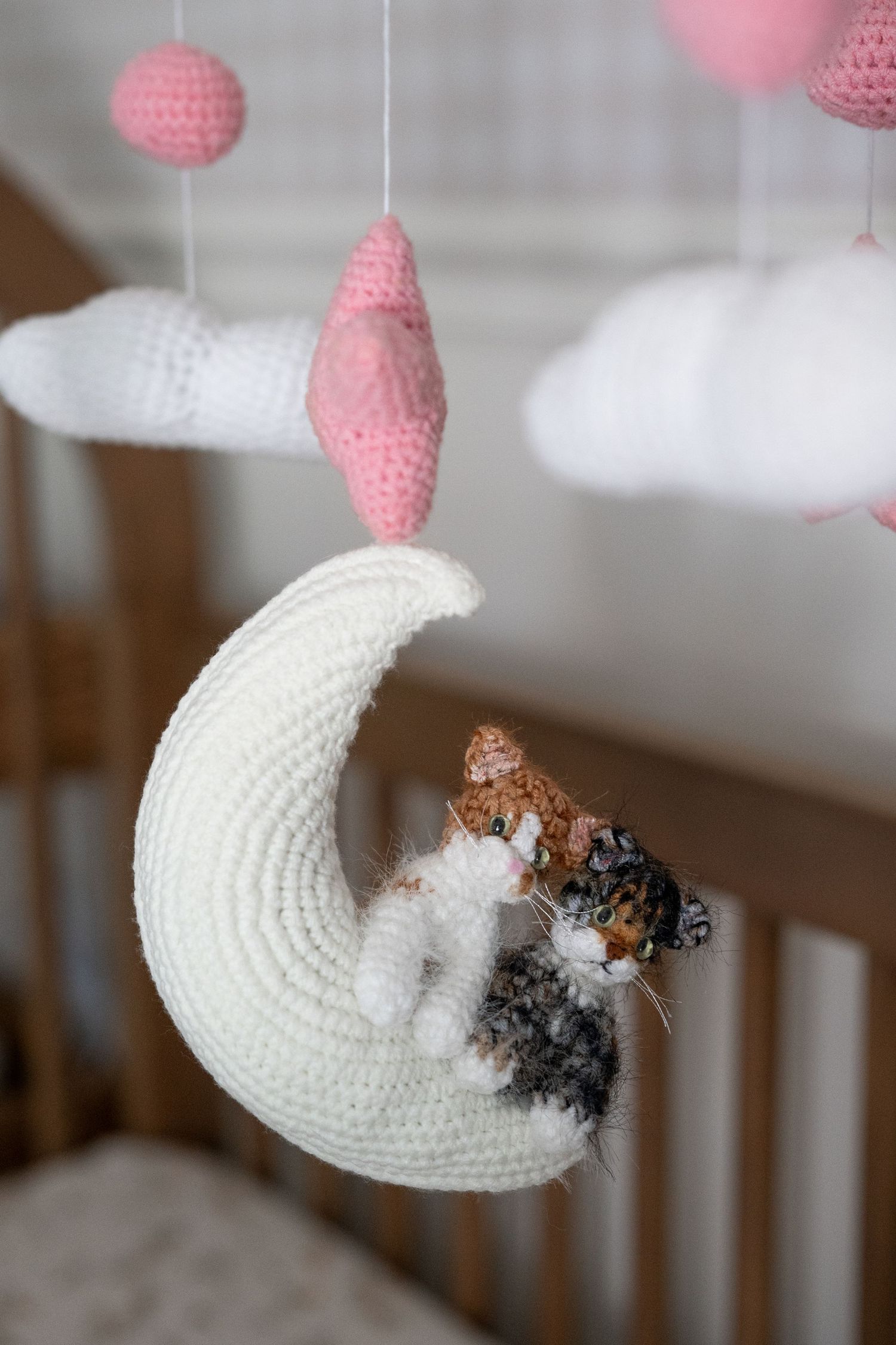 Crocheted white moon and pink star mobile hanging above crib.