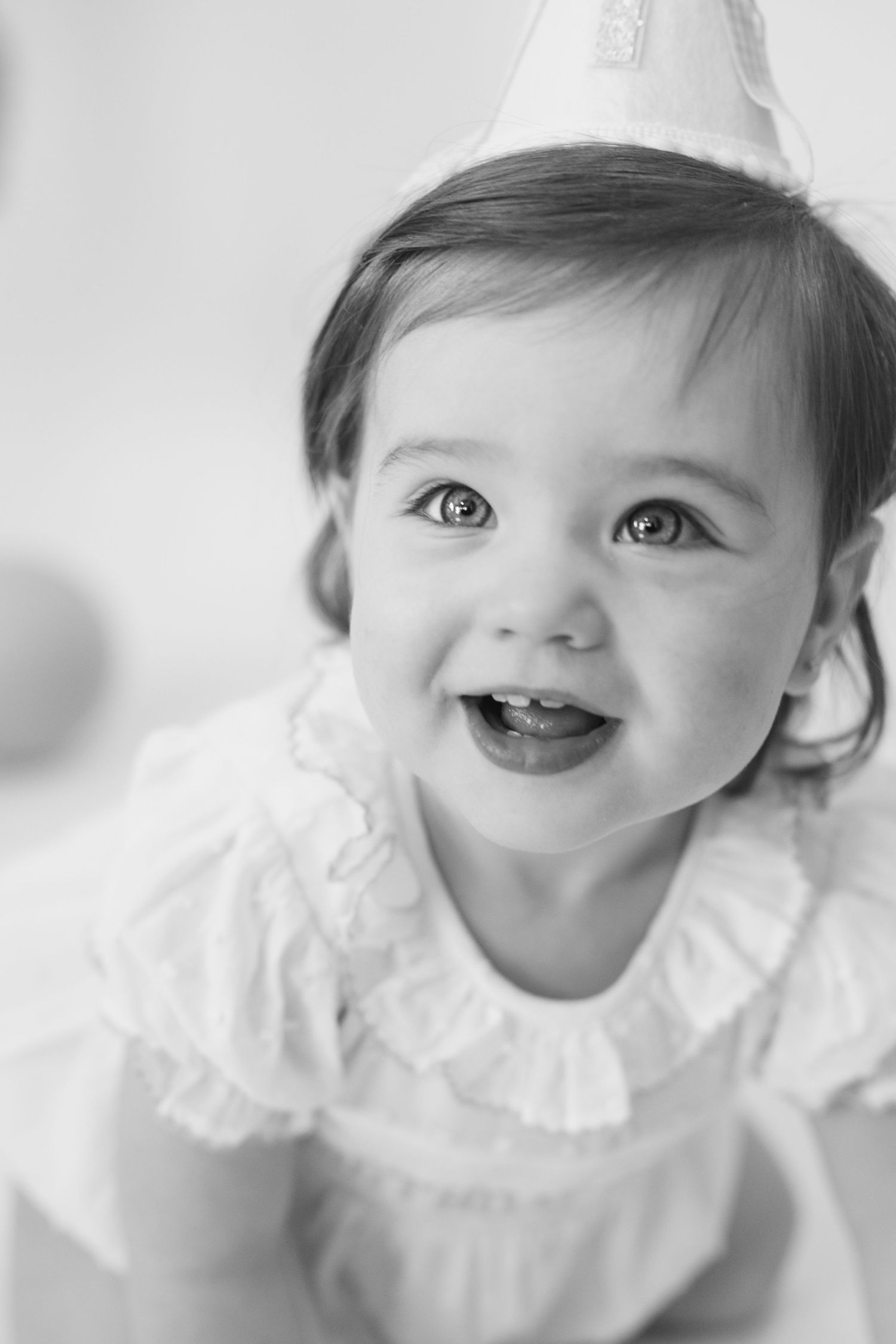 Black and white portrait series of baby in white ruffled dress showing various expressions.