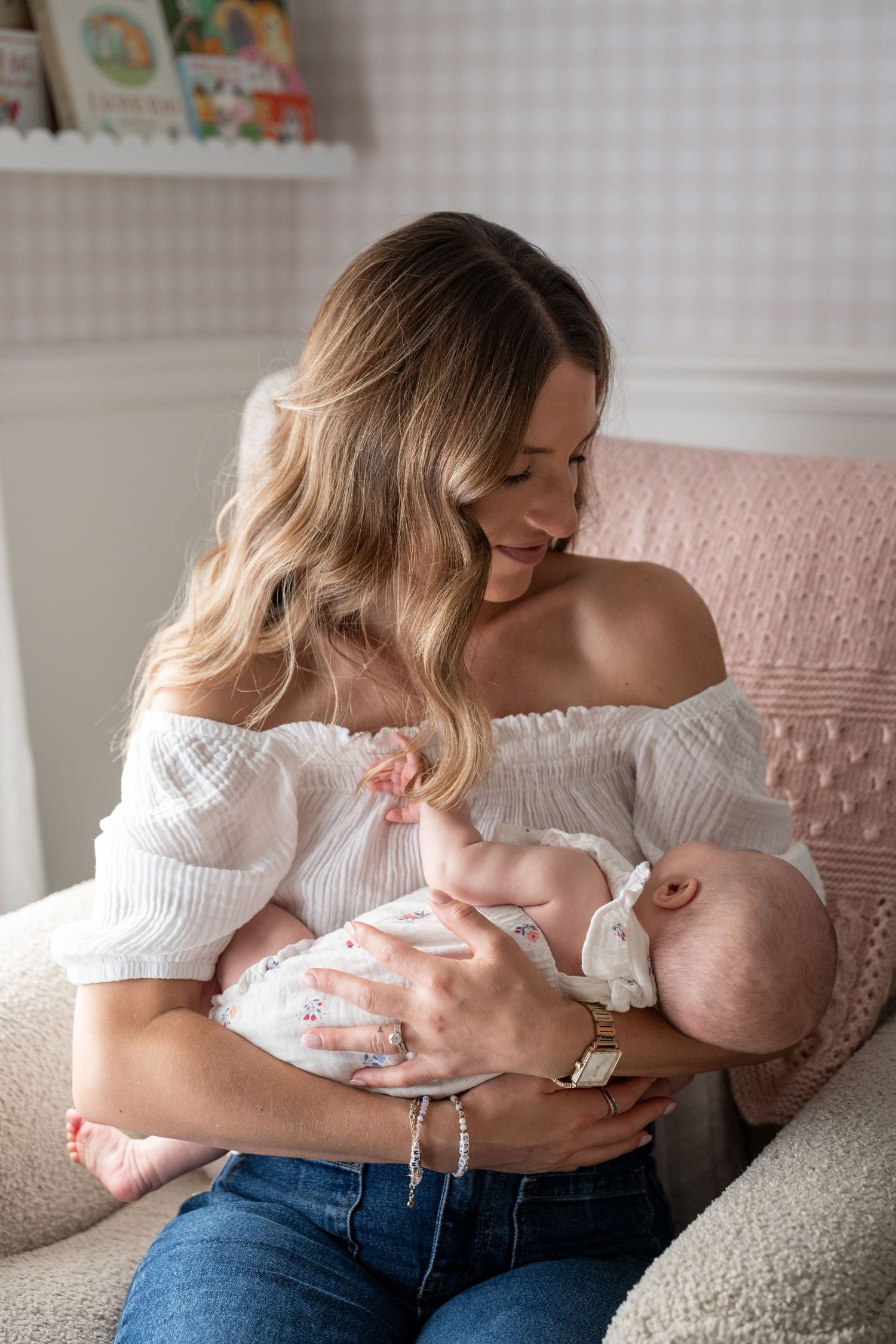 Tender parenting moment captured on a gray couch with pink pillows.