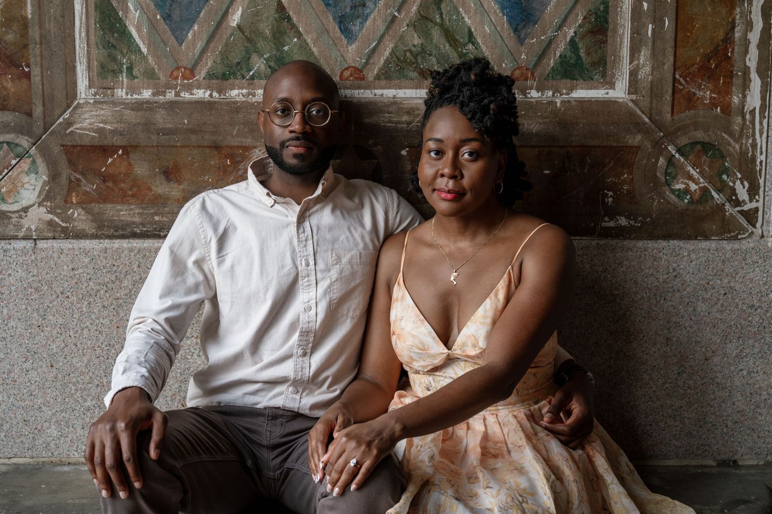 Elegant engagement photo session against industrial brick wall background.