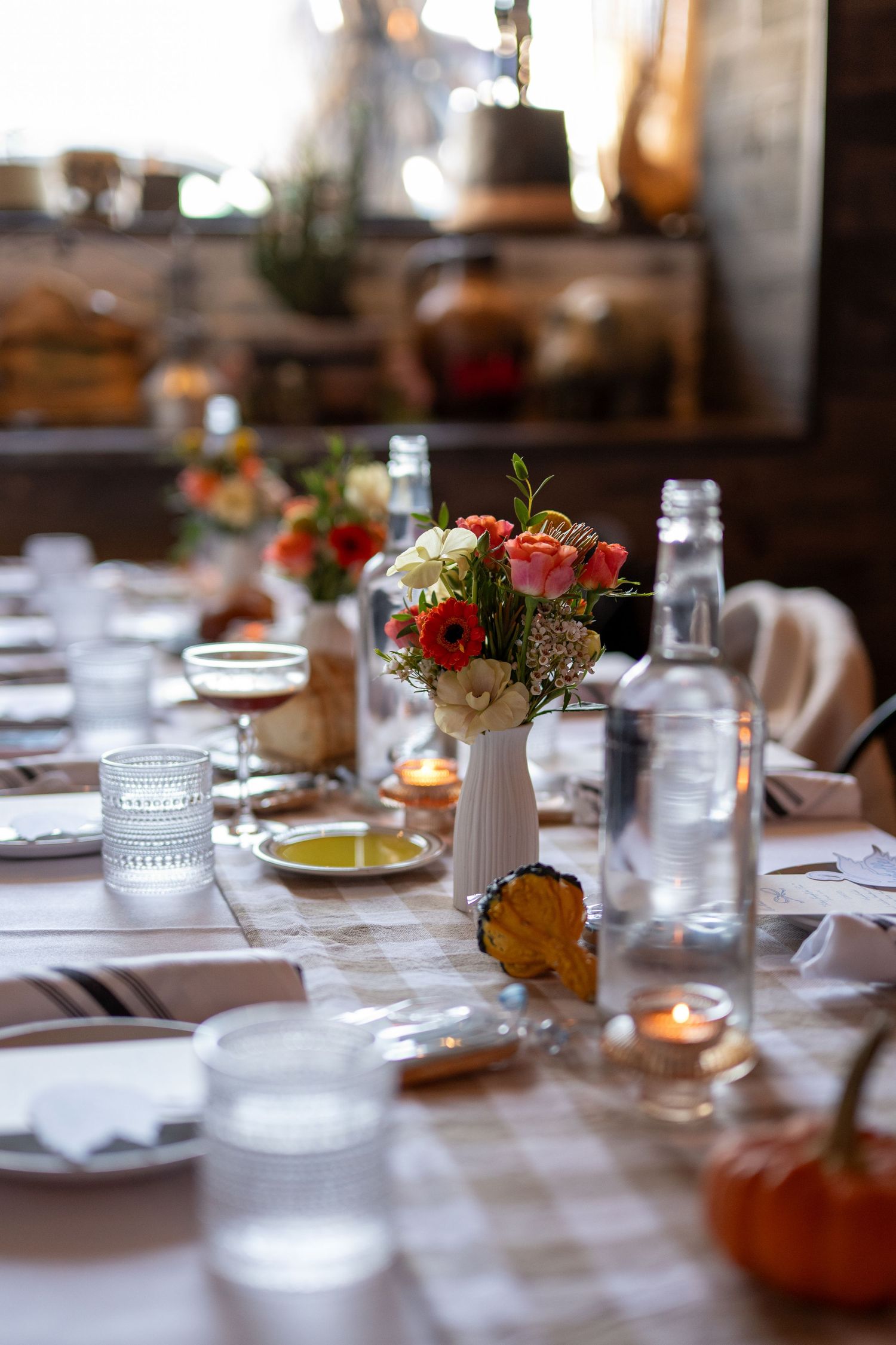 Elegant table settings at a dinner party with white linens, glassware, and floral centerpieces lit by candlelight.