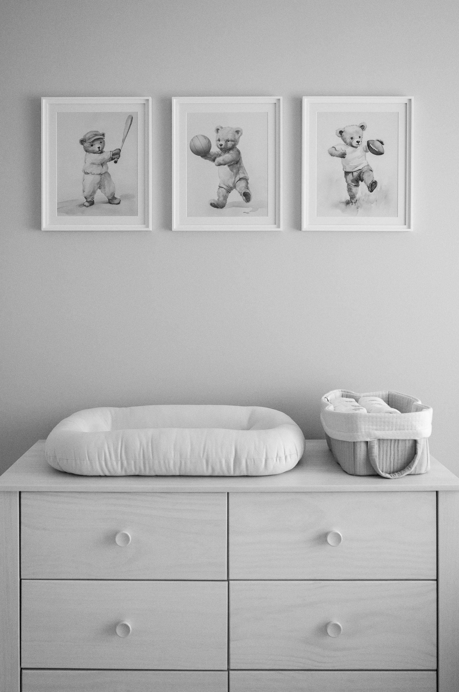 Minimalist nursery with white dresser and framed artwork displaying baby photos.