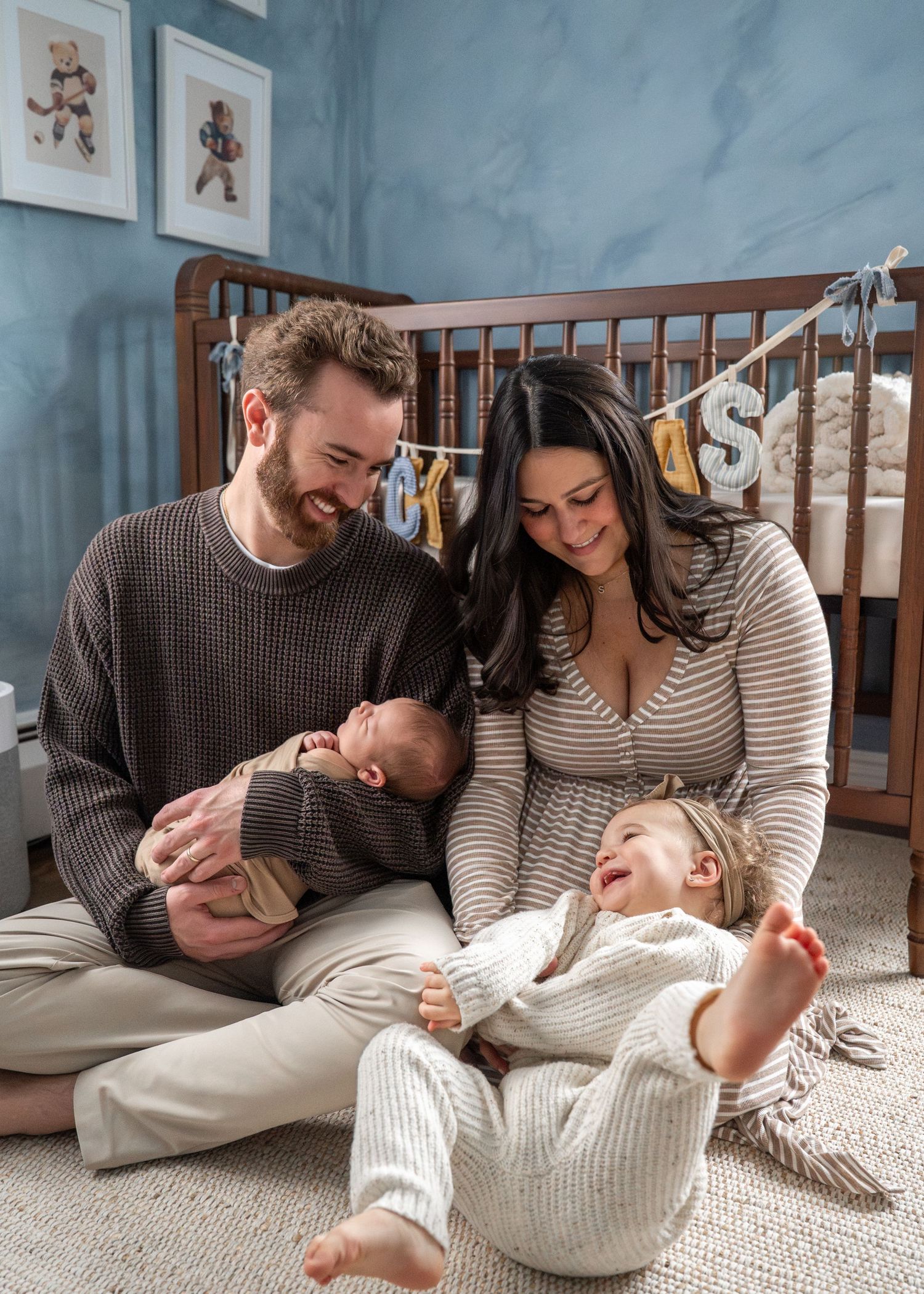 Happy family sharing joyful moment together in nursery with blue walls and wooden crib.