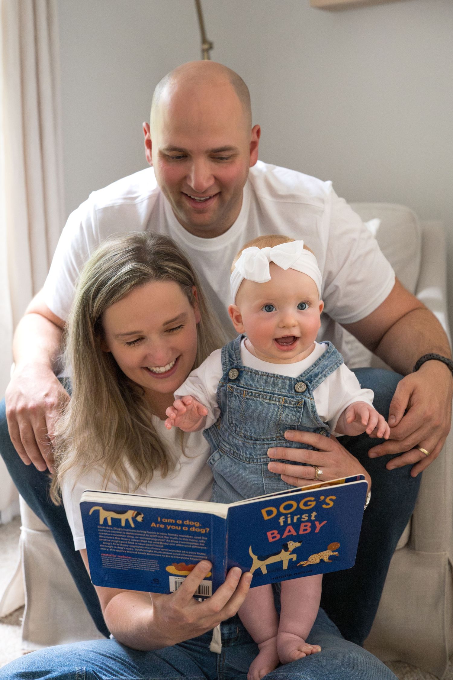 Happy family reading a children's book together while sitting on a cozy armchair at home.