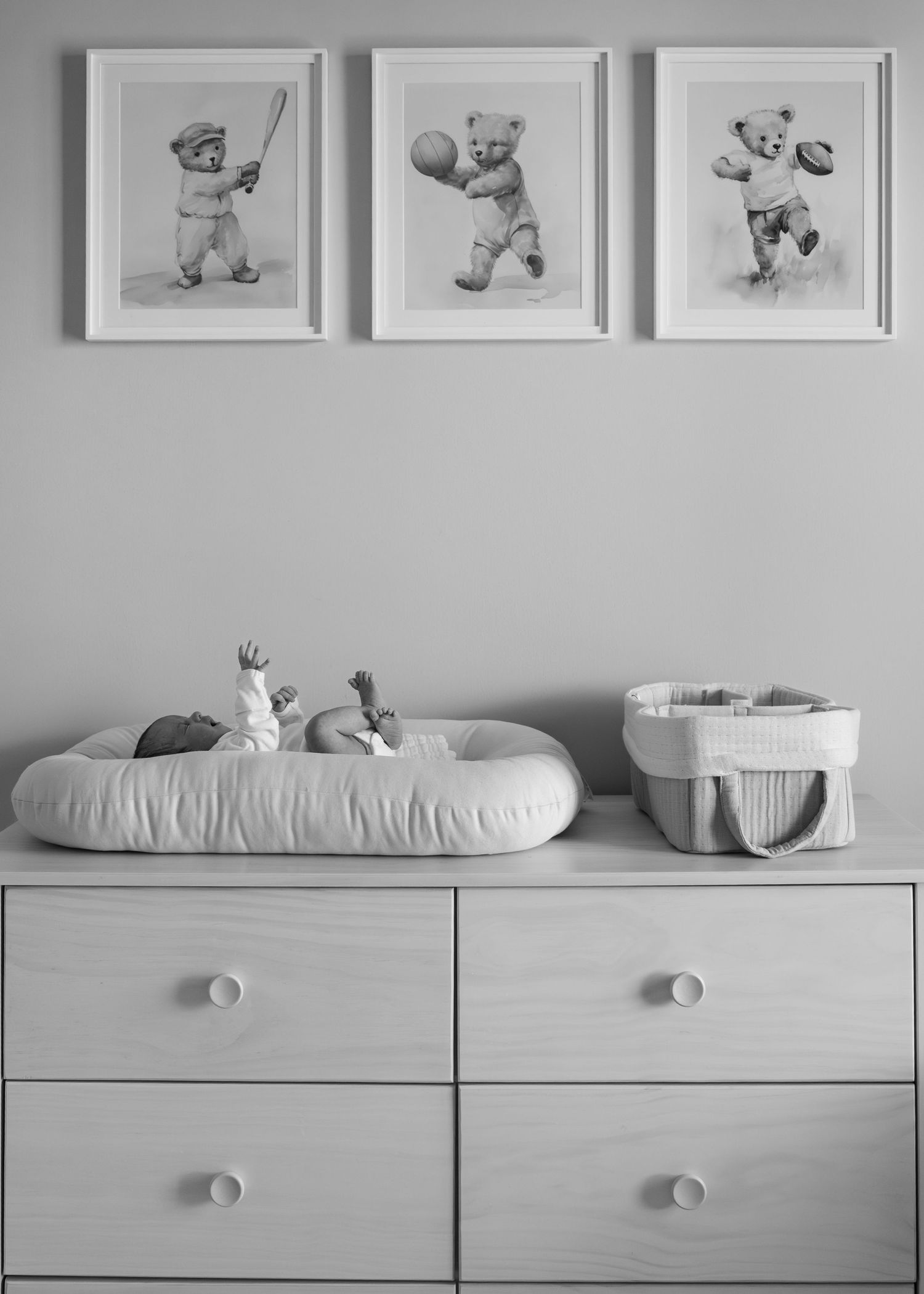 Nursery dresser with teddy bear artwork and baby lounger on top.