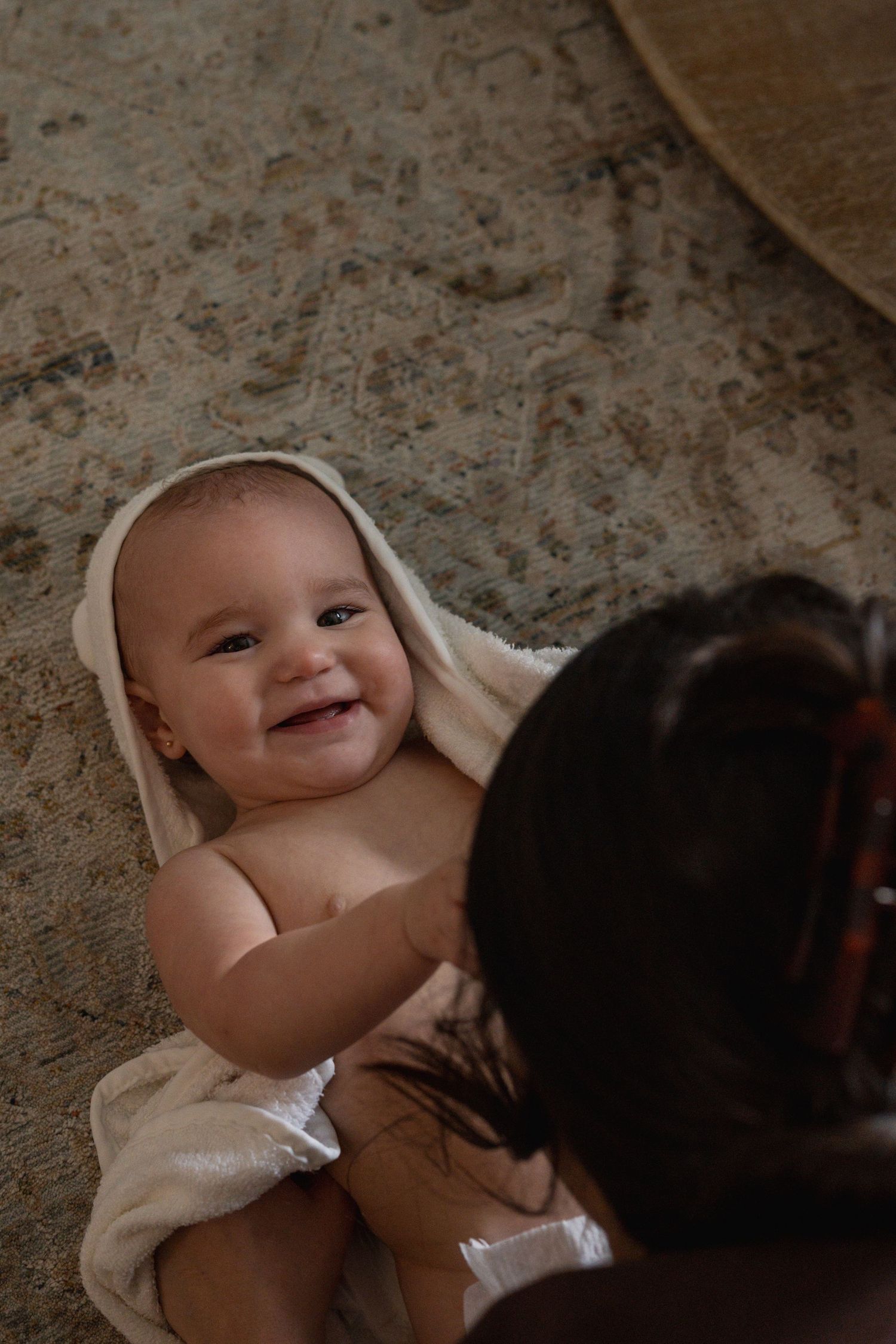 A baby lies on the floor while interacting with a dark-colored pet in a sequence of photos.