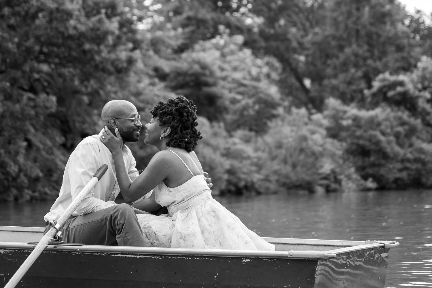 Black and white photos showing a couple sharing intimate moments while rowing on a lake.