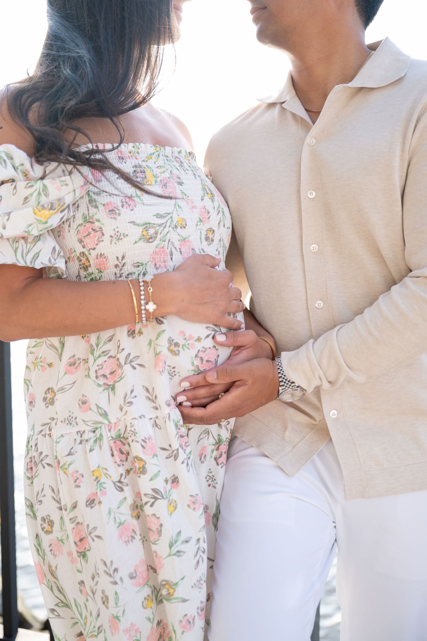Close-up shots of couple in floral dress and white outfit holding hands and embracing.