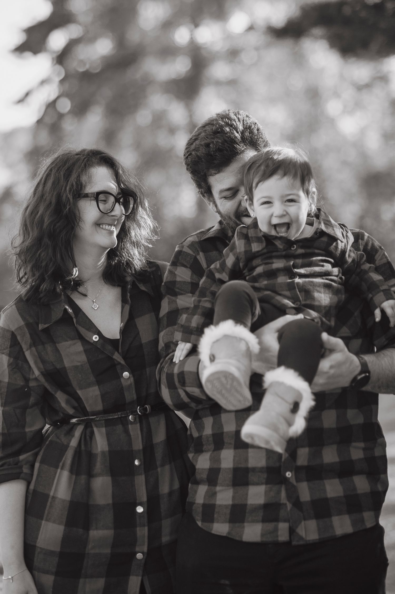 A series of black and white photos showing playful moments in matching plaid shirts outdoors.