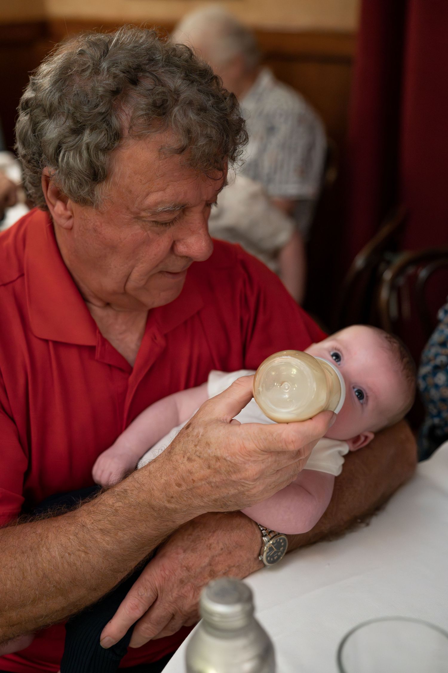 A sequence showing someone bottle feeding a baby at a table.