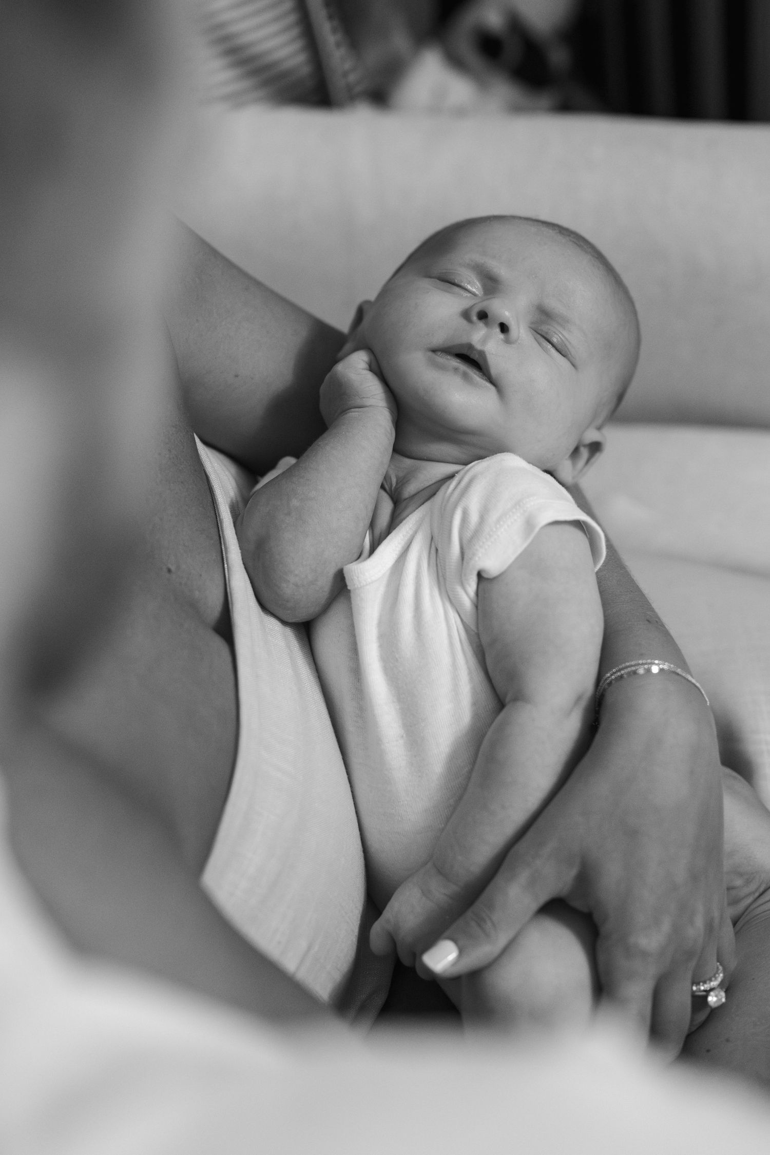 Peaceful sleeping infant in white onesie being gently cradled.
