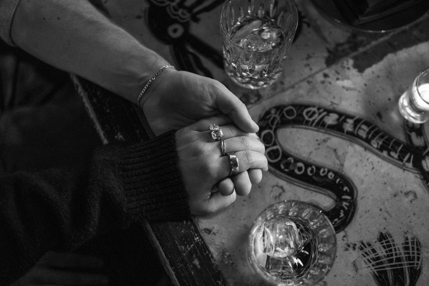 Black and white image of hands holding a crystal ball with tarot cards and mystical objects on a table.