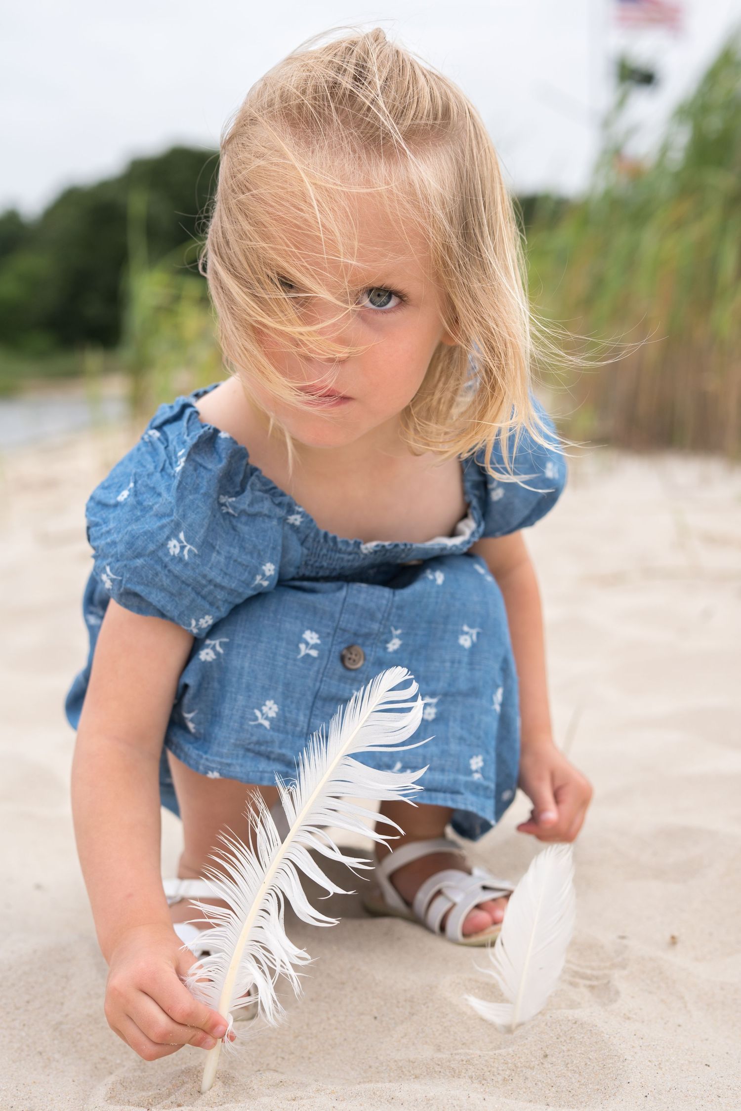 Child in denim exploring and playing in beach sand, showing curiosity and wonder.