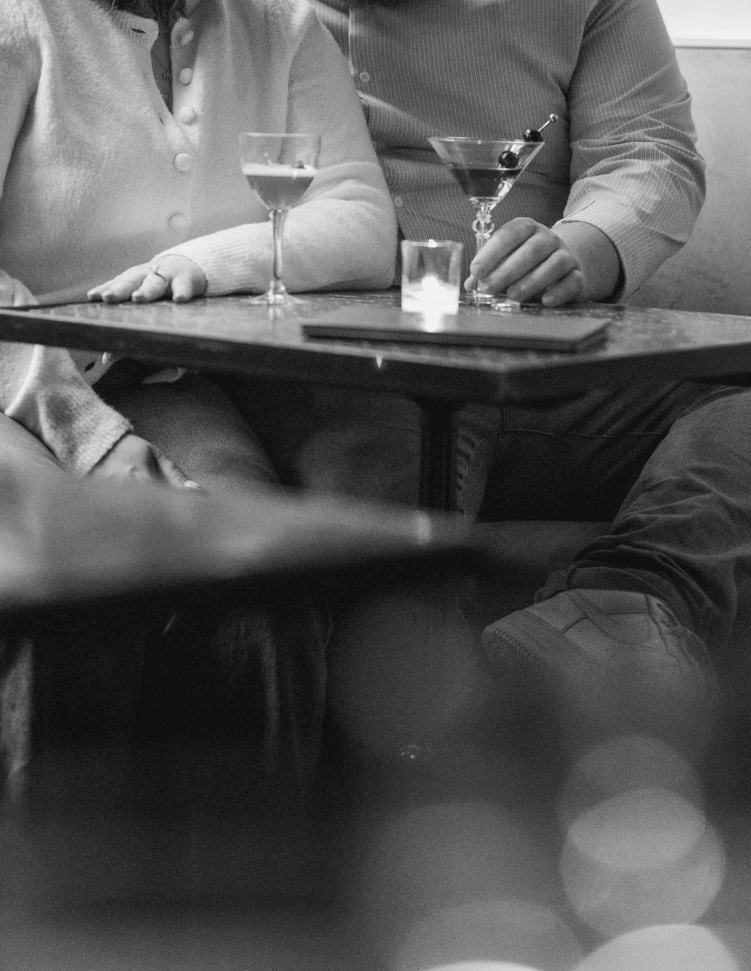 A black and white image of people sitting at a restaurant table with drinks.