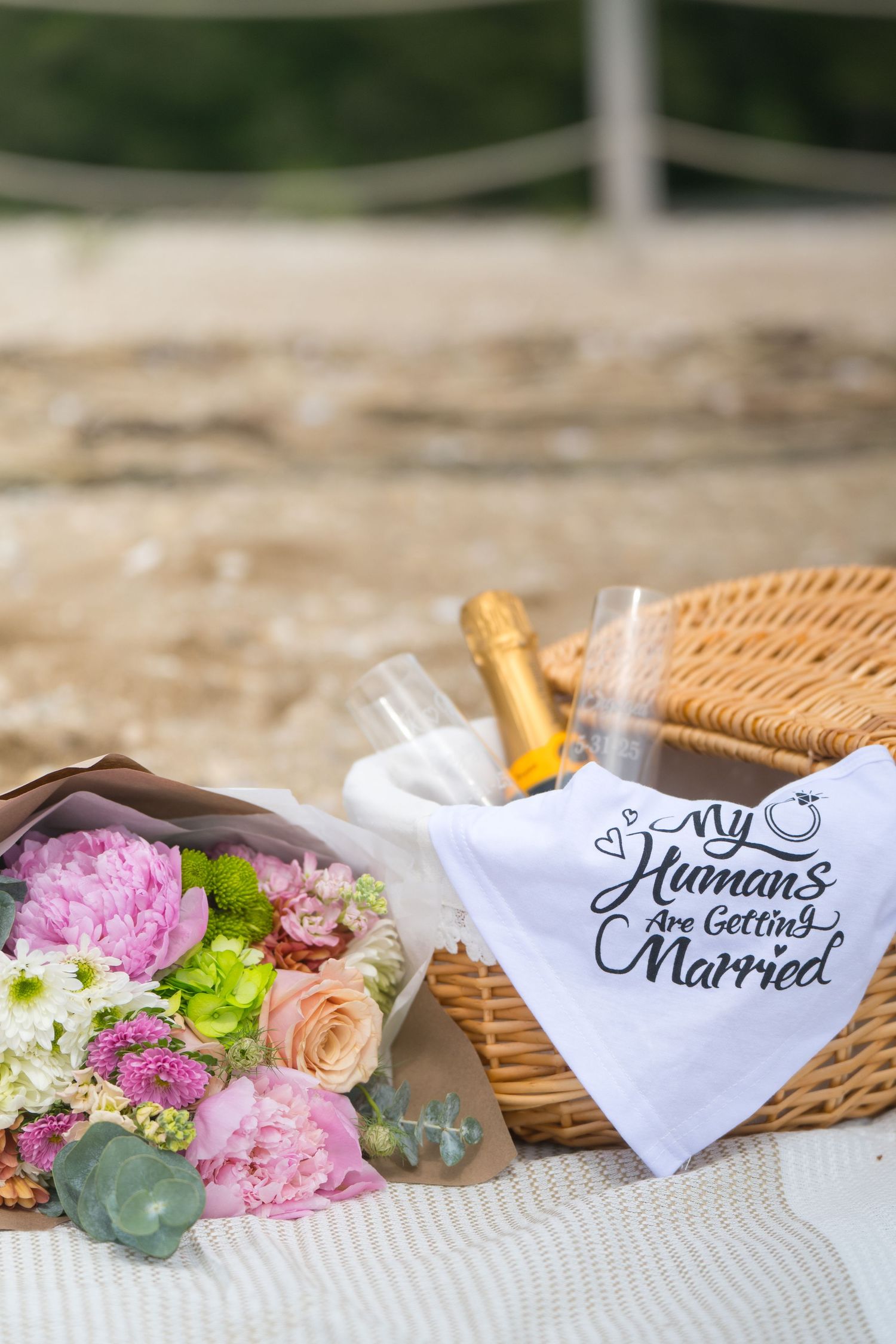 Wedding decorations featuring floral arrangements with pink roses and white napkins embroidered with 'Getting Married' text.