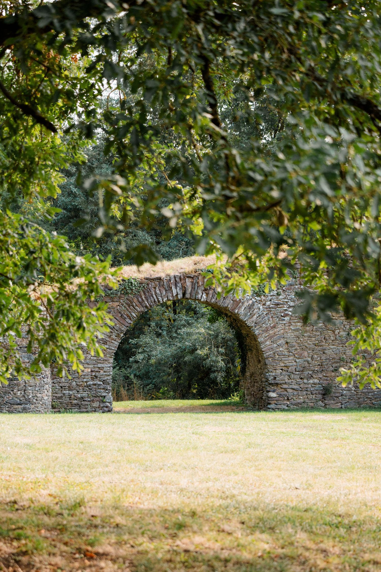 Ancien arc en pierre dans un parc romantique, décor parfait pour photos de mariage. Château de cop-choux