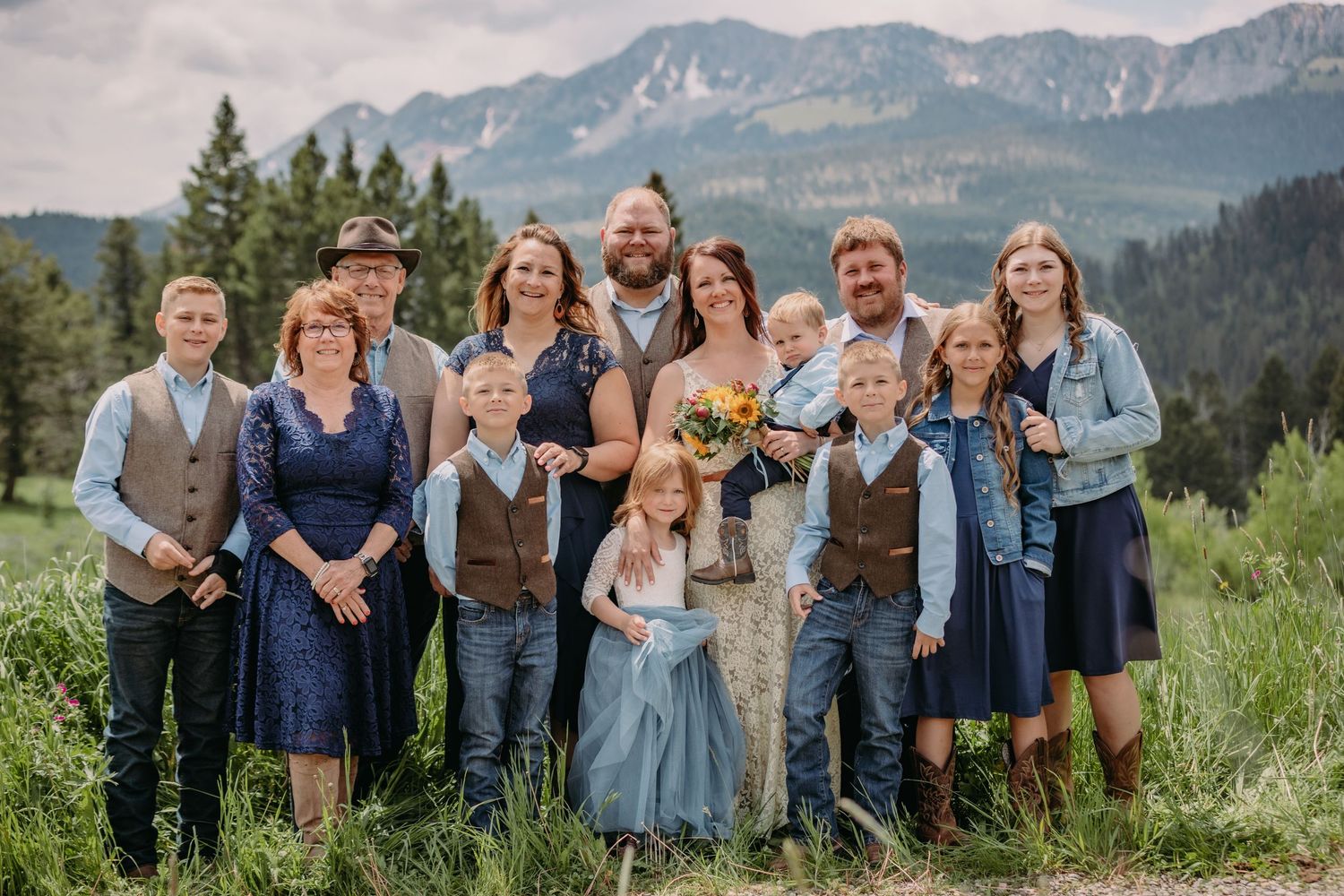Wedding party group photo with mountains and evergreen trees in background.