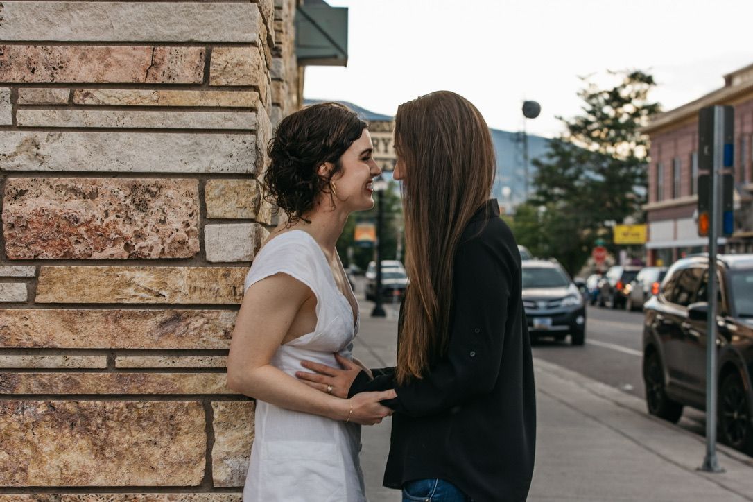 Two people share an emotional moment against urban brick wall background.