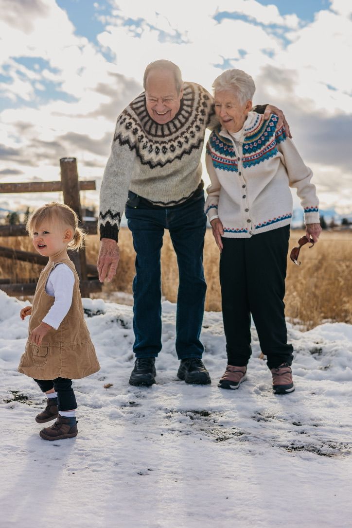Winter family scene with Nordic sweaters and snowy ground during golden hour.