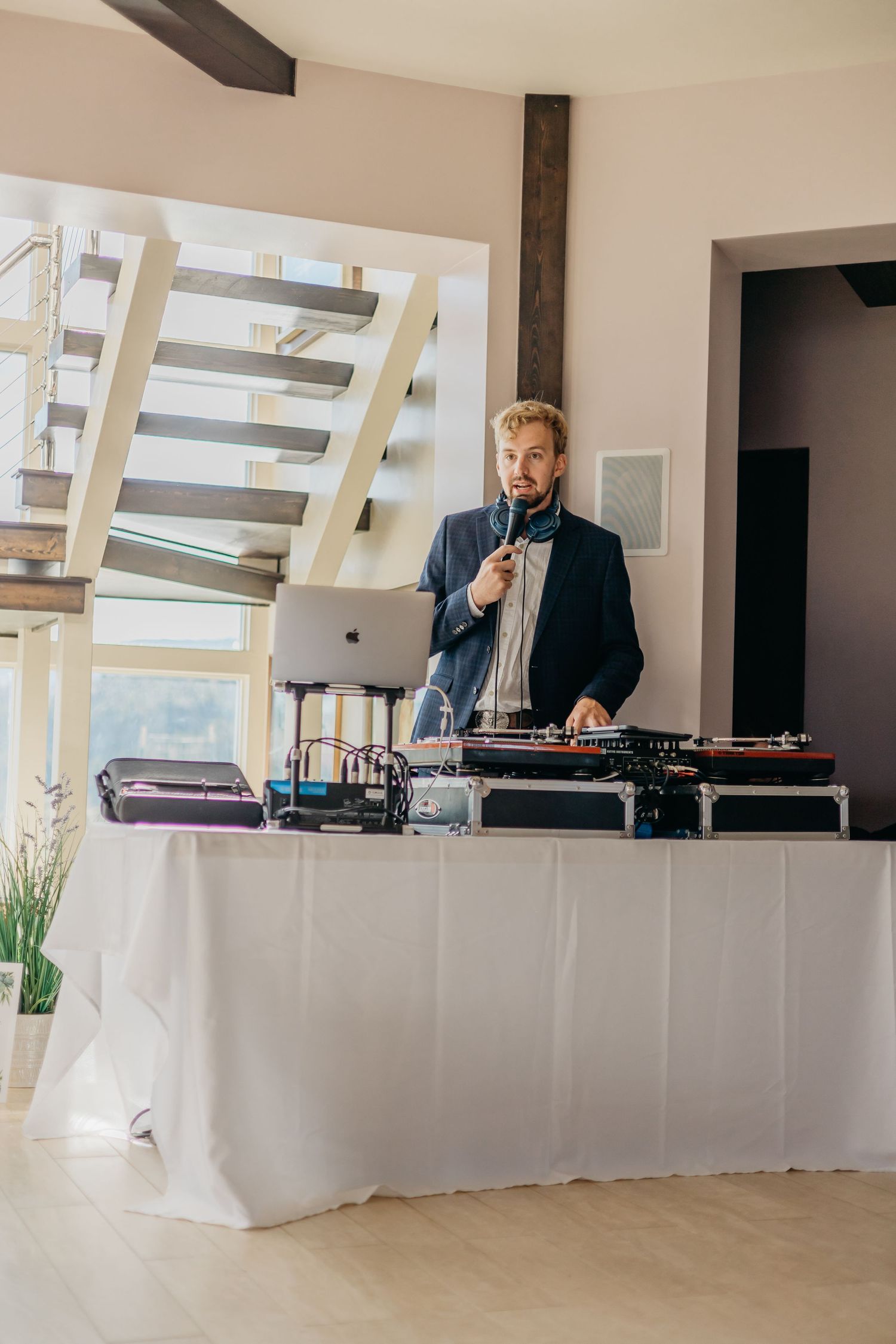 Wedding DJ setup with white-draped tables and professional equipment.