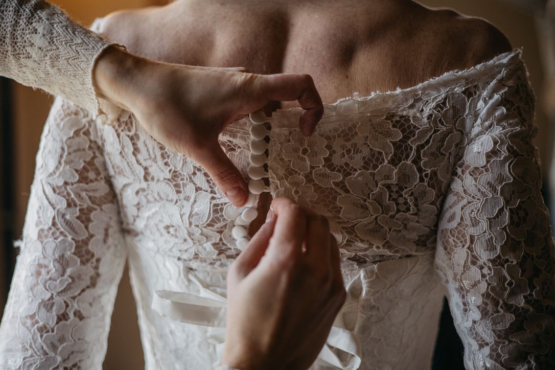 Detailed close-up of wedding dress bodice showing intricate lace patterns and beading.