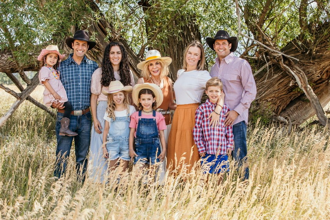Casual group portrait in a rustic outdoor setting with mountains and tall grass.